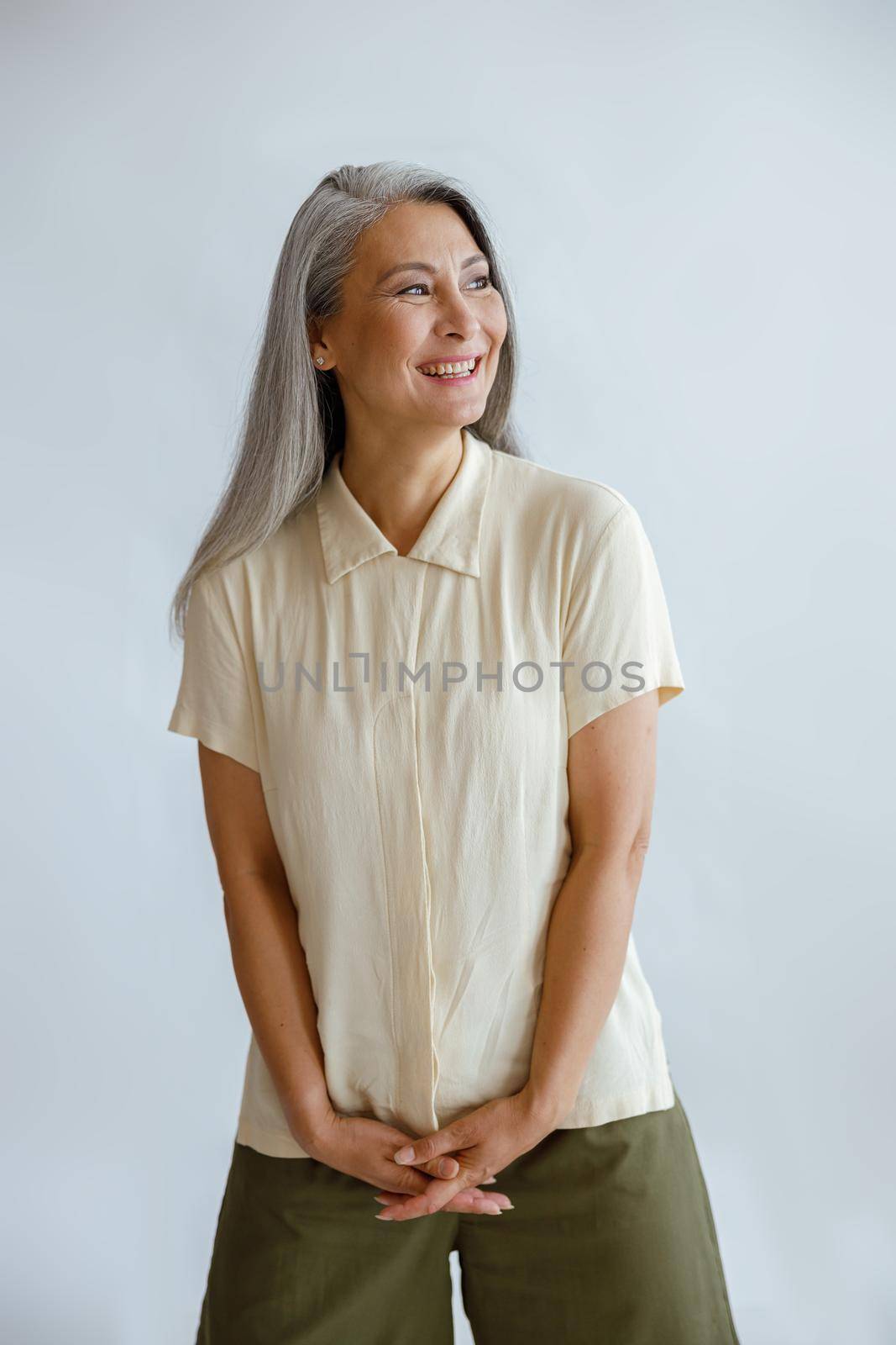 Joyful middle lady in stylish casual clothes stands on light grey background by Yaroslav_astakhov