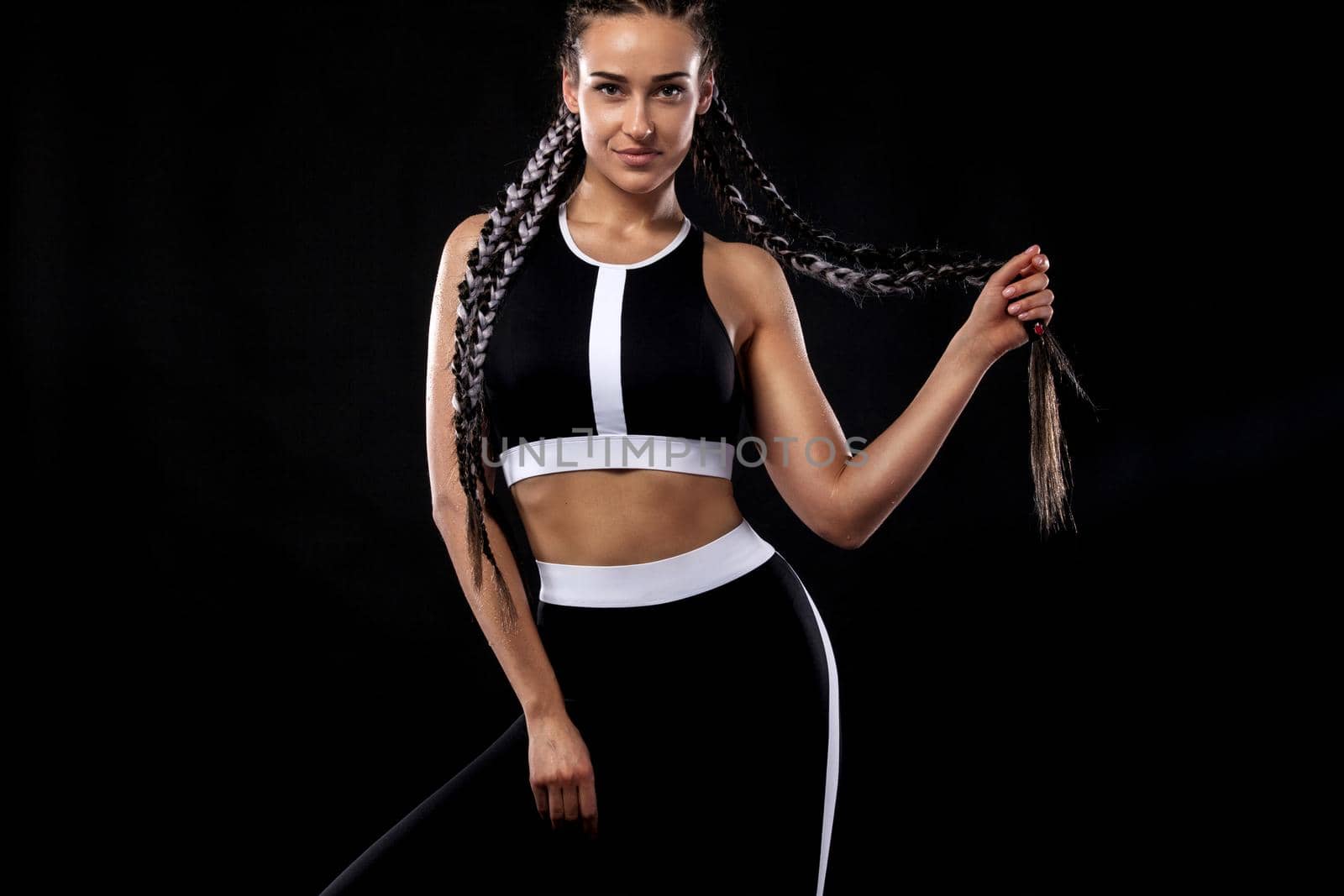 A strong athletic woman on black background wearing in black sportswear, fitness and sport motivation. Sport concept with copy space. by MikeOrlov