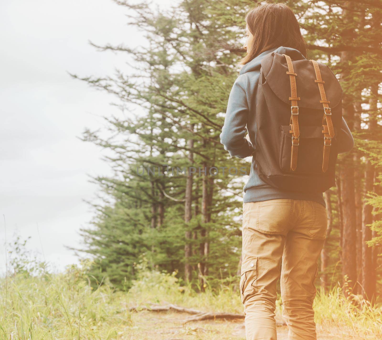 Hiker young woman with backpack walking in summer forest outdoor.