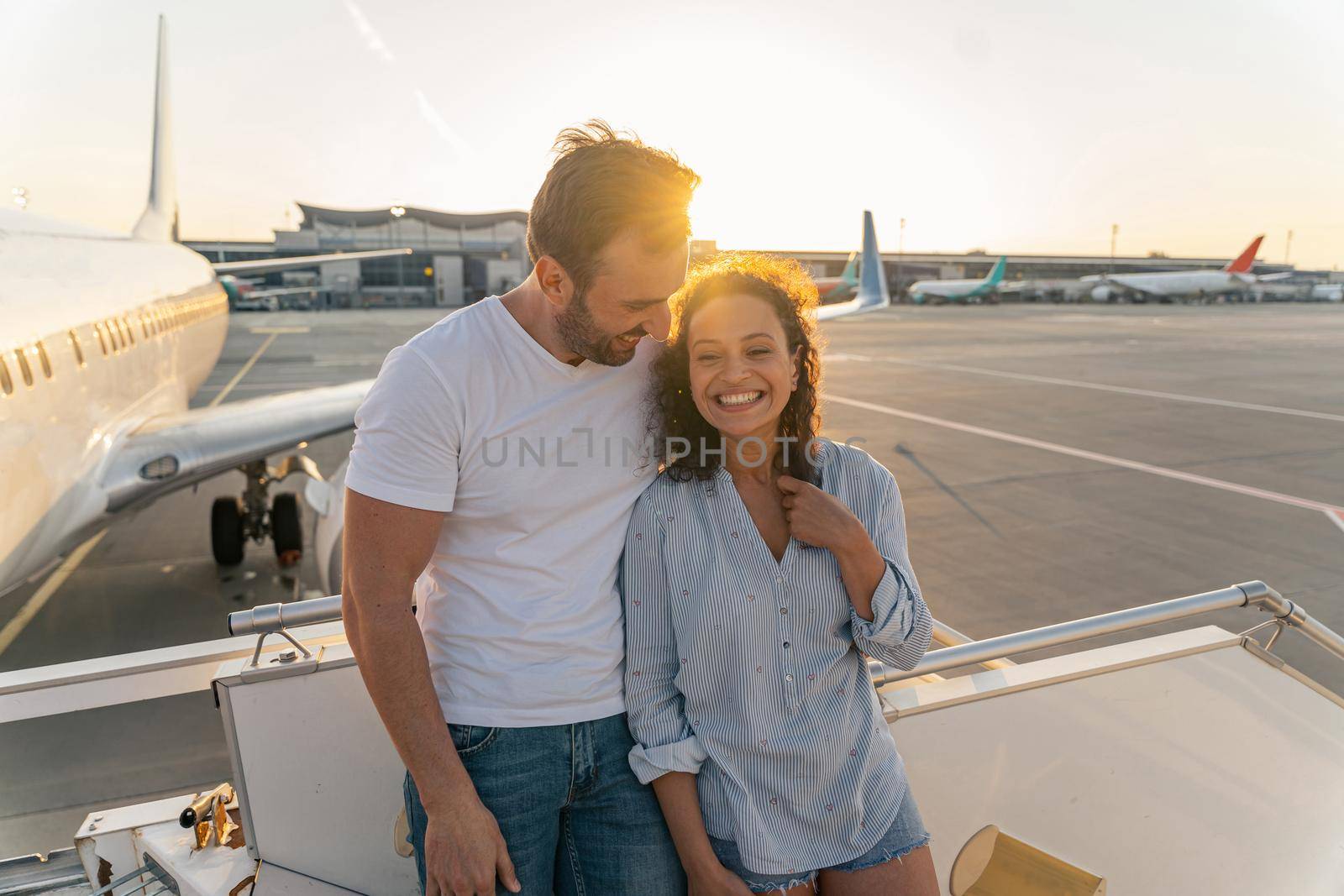 Couple in love standing on the plane ladder before the flight by Yaroslav_astakhov