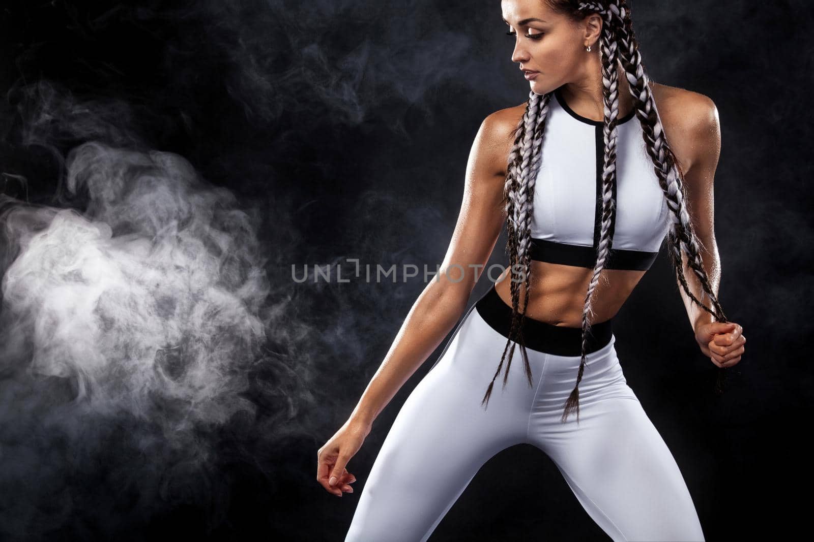 A strong athletic woman on black background wearing in white sportswear, fitness and sport motivation. Sport concept with copy space. by MikeOrlov