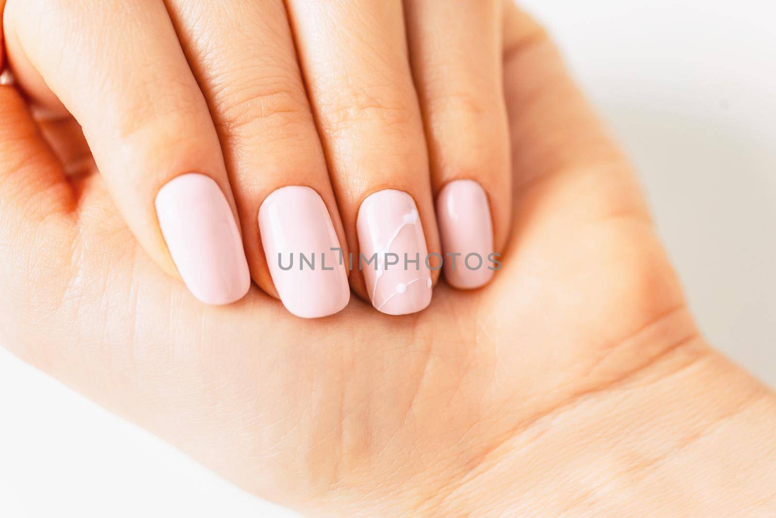 Woman’s hand with manicure of pink pastel color and art design, close-up.