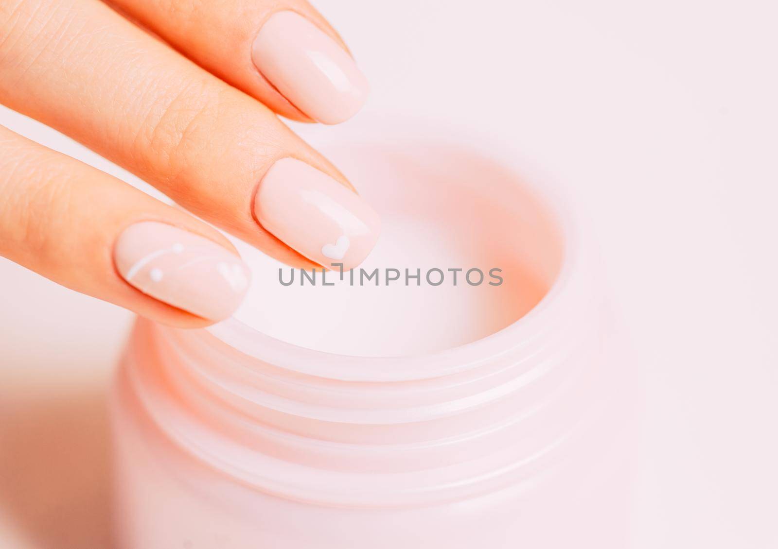 Close-up of female hand using moisturizing cream from jar, concept of beauty and skincare.