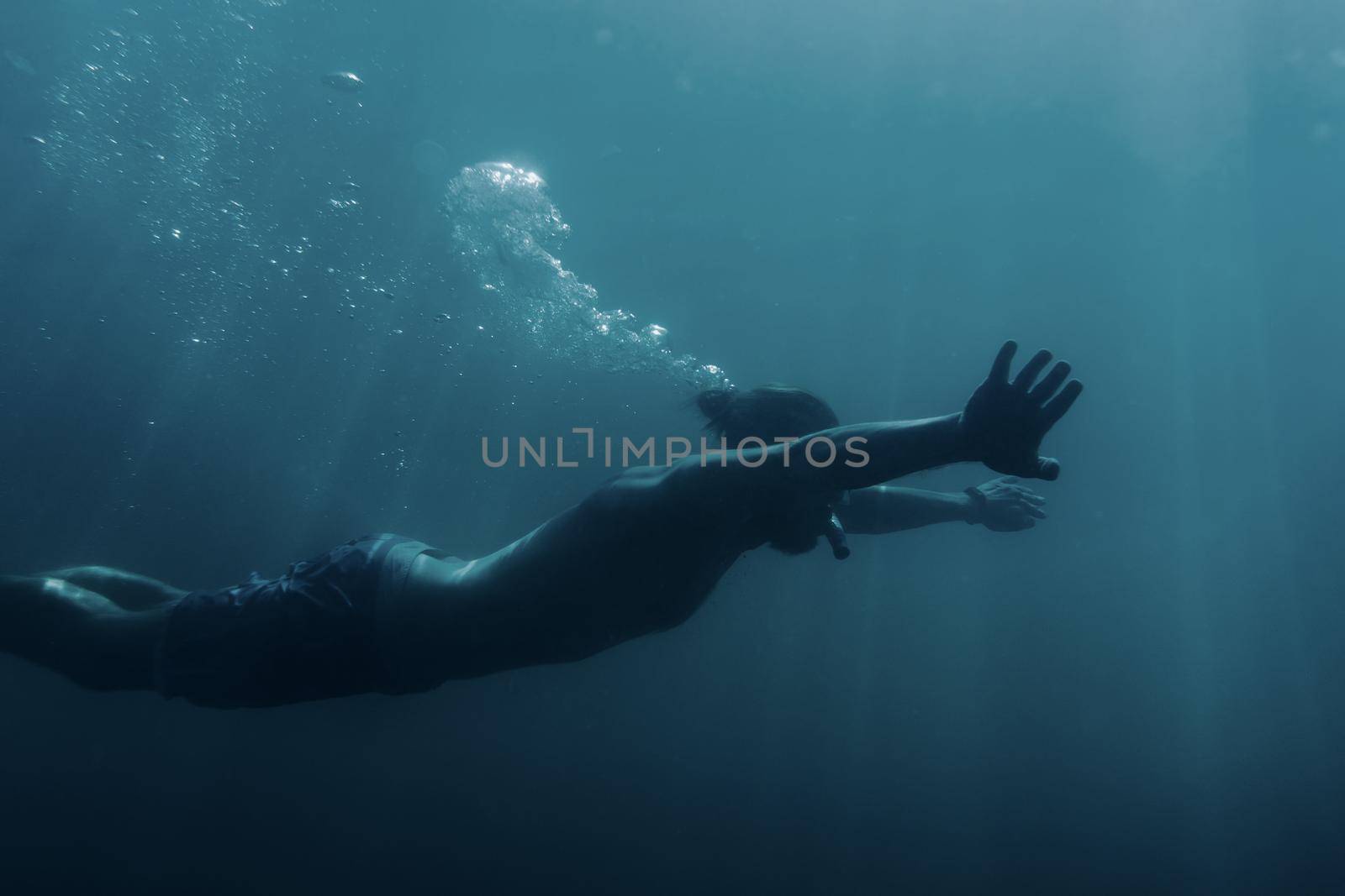 Freediver young man swimming underwater and using breaststroke technique.