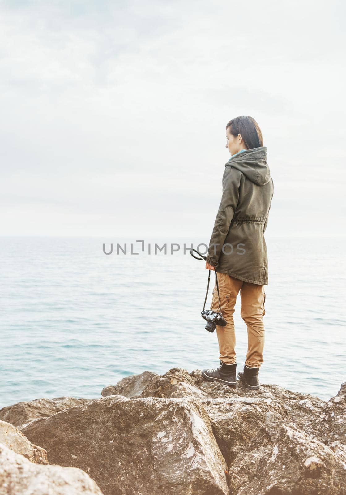 Traveler woman standing on coast with photo camera. by alexAleksei