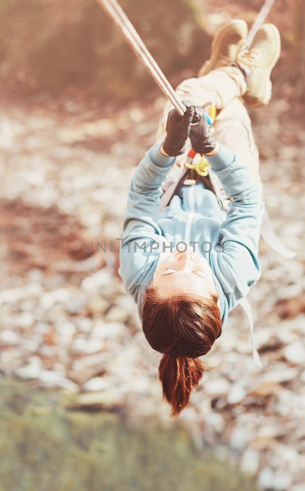 Sporty woman crossing a river with tyrolean traverse. by alexAleksei