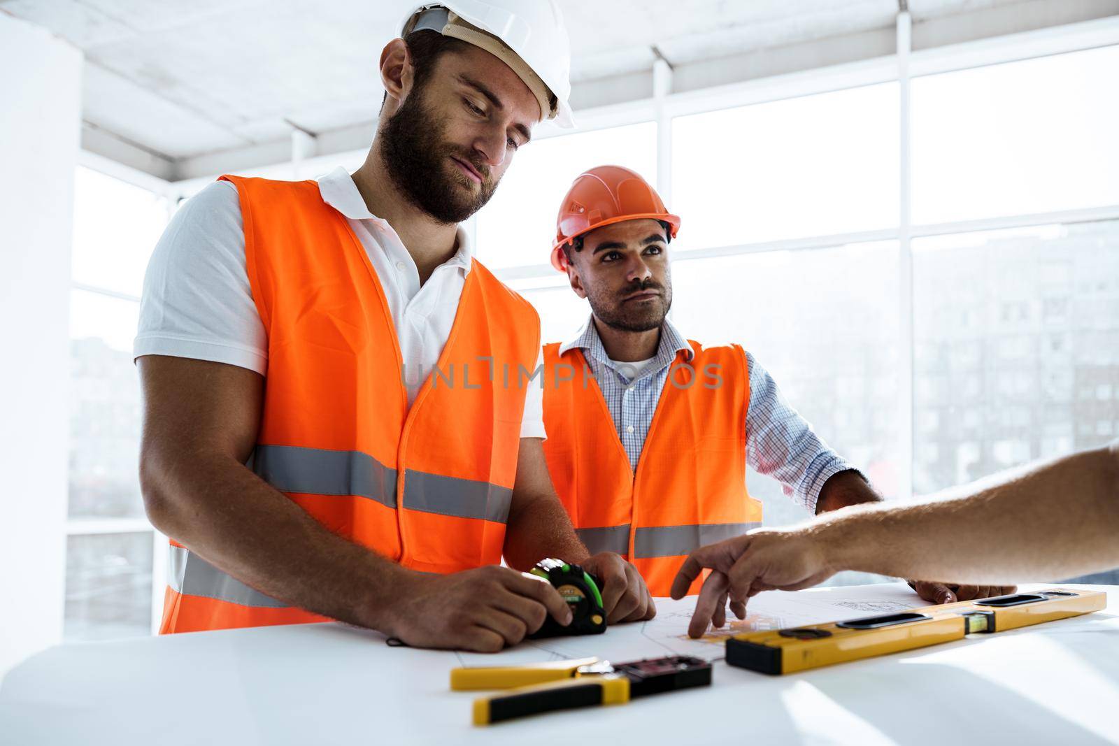 Two young engineers man looking at project plan on the table in construction site