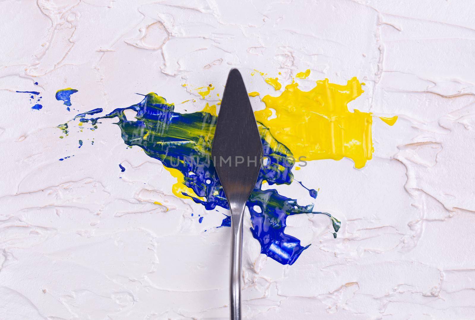 a painting palette knife isolated on a white painted background painting a blue and yellow with copy space. by lunarts