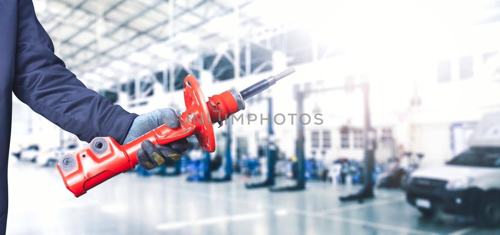 Mechanic hand holding a front shock absorber of the car in the repair garage