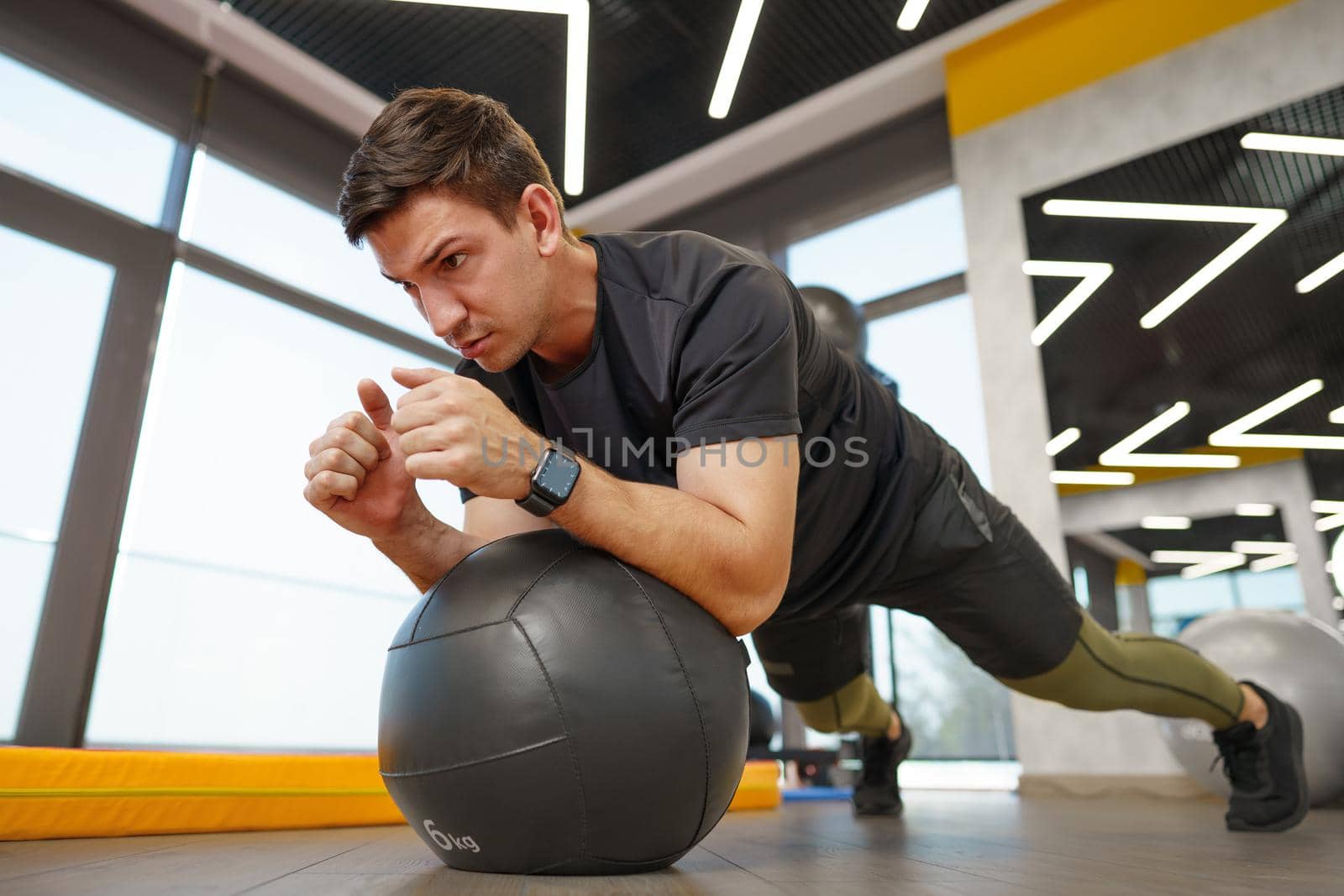Fit young man exercising with fitness ball in a gym, close up