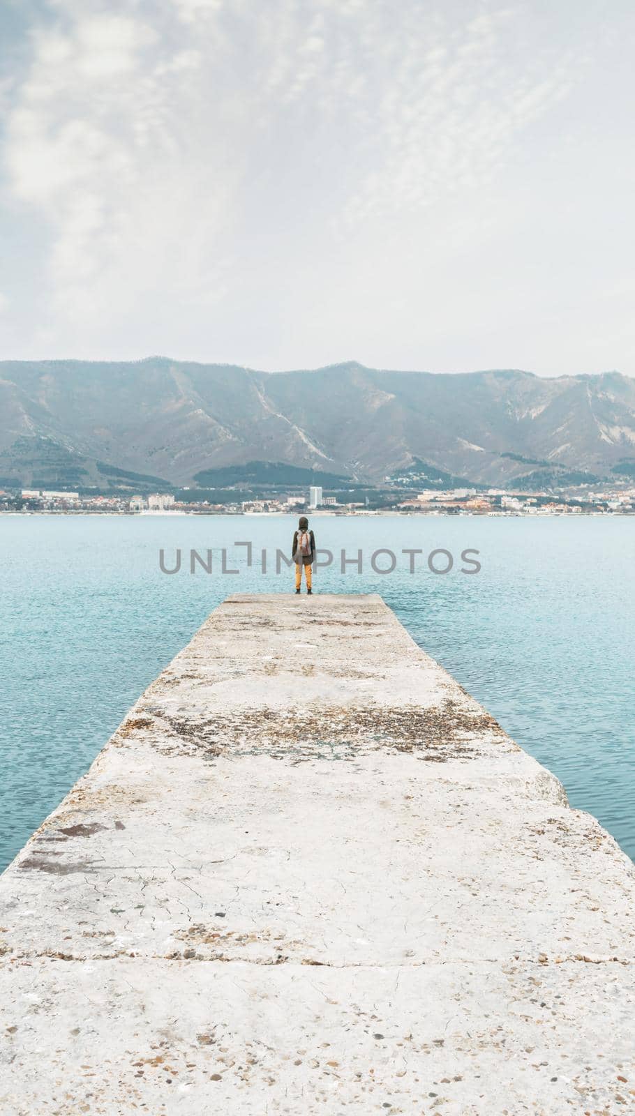 Backpacker standing on pier. by alexAleksei