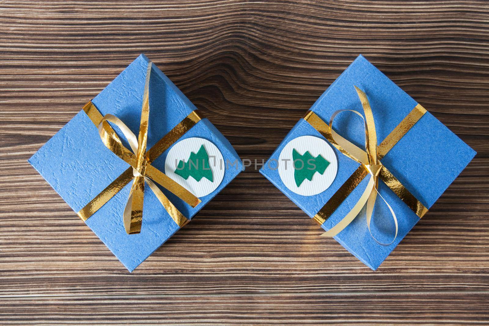 Blue gift boxes with golden ribbons on a brown wooden background for Christmas and New Year