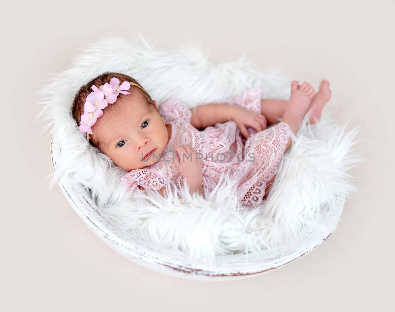 Lovely newborn girl with open eyes in beautiful dress