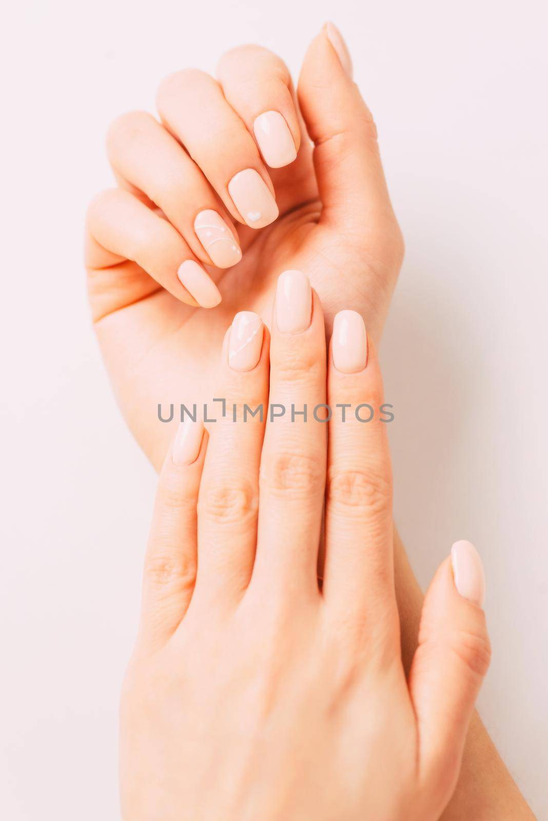 Hands of young woman with beige manicure. by alexAleksei