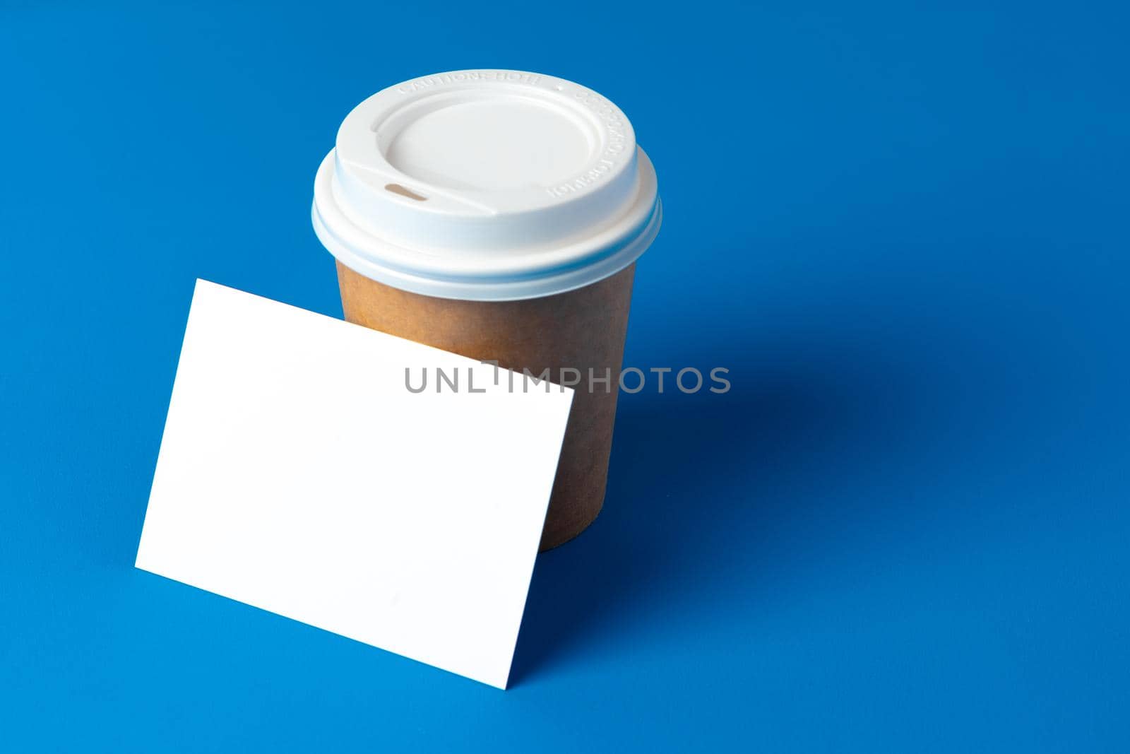 Blank takeaway coffee cup and white businesscards with copy space