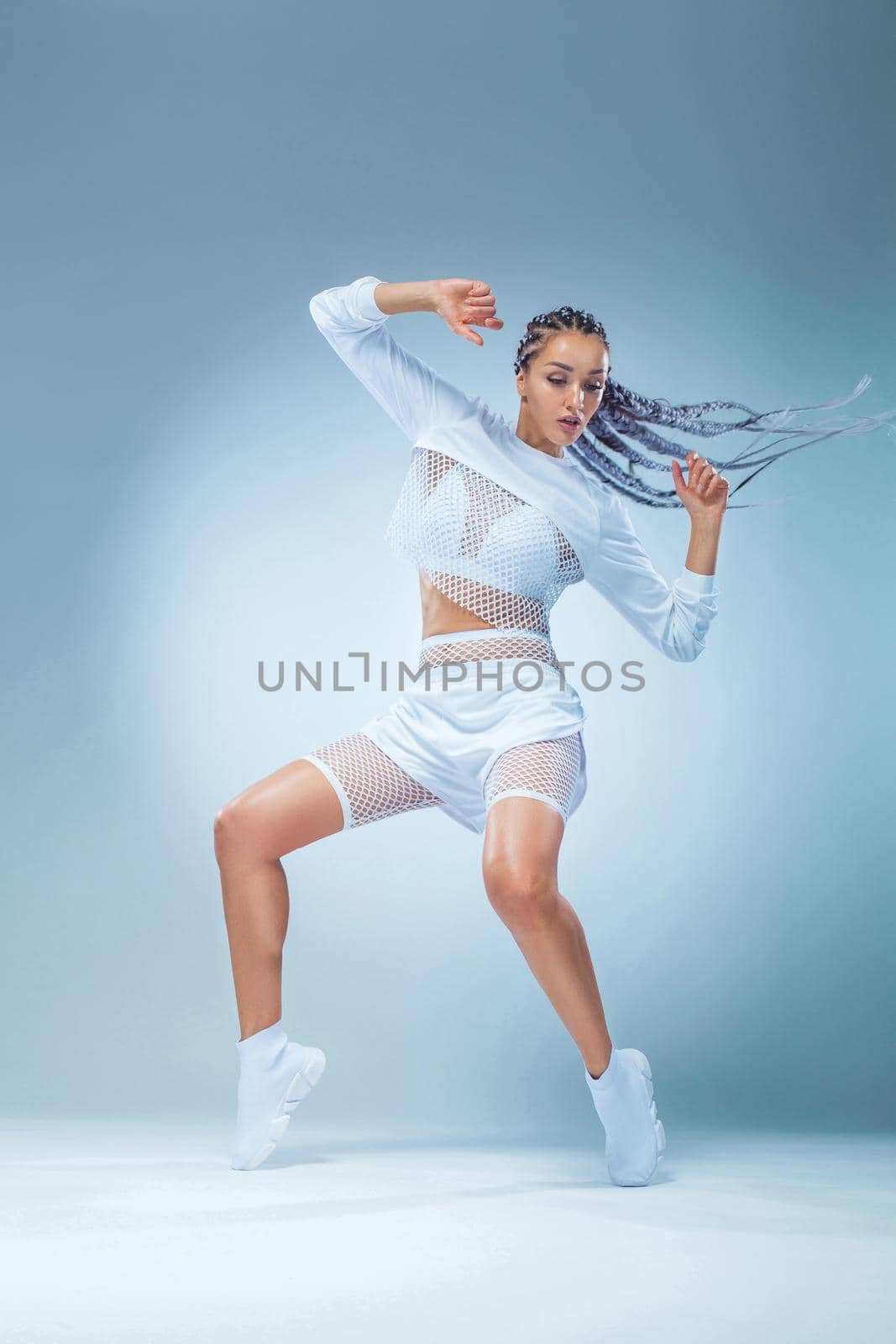 Attractive excited fitness girl dancer in sportwear dance isolated over blue background. Fashion and livestyle concept. by MikeOrlov