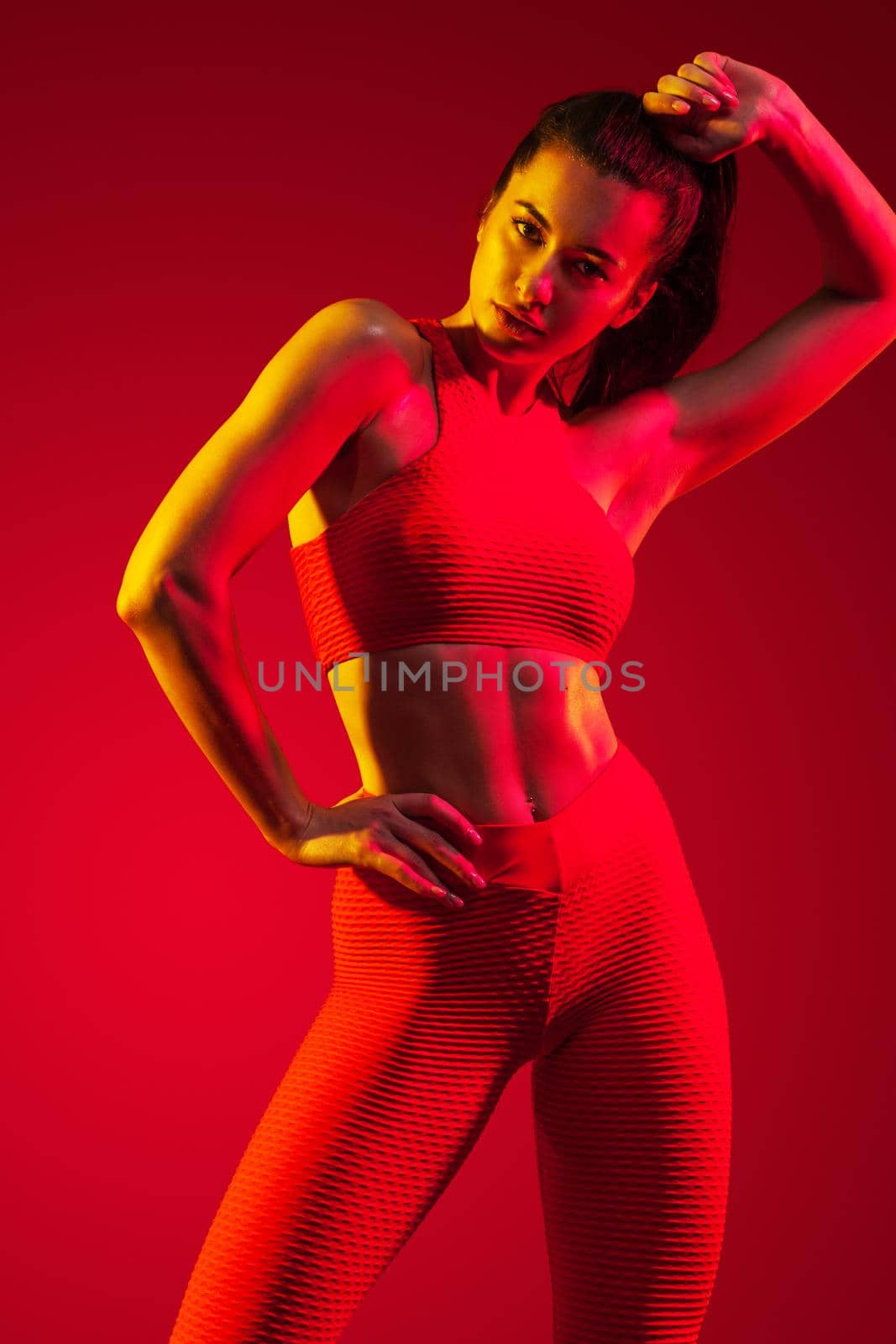 A strong athletic, woman dancer, posing on red background wearing in the sportswear, fitness and sport motivation with copy space. by MikeOrlov