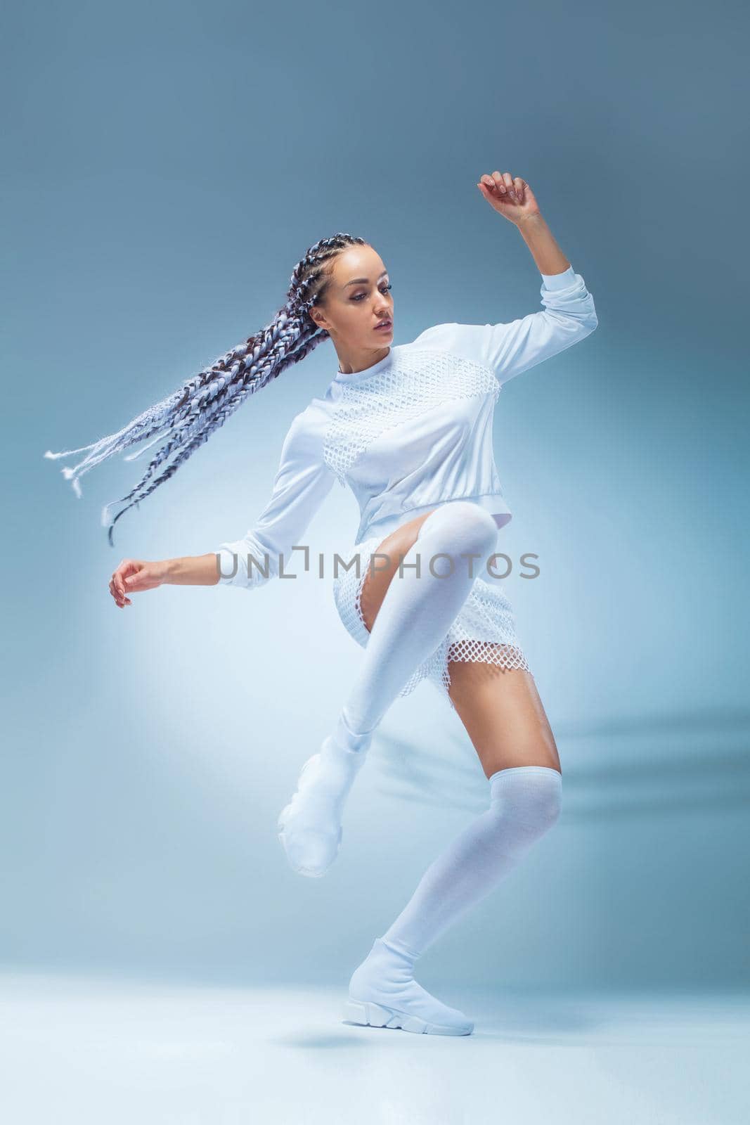 Attractive excited fitness girl dancer in sportwear dance isolated over blue background. Fashion and livestyle concept. by MikeOrlov