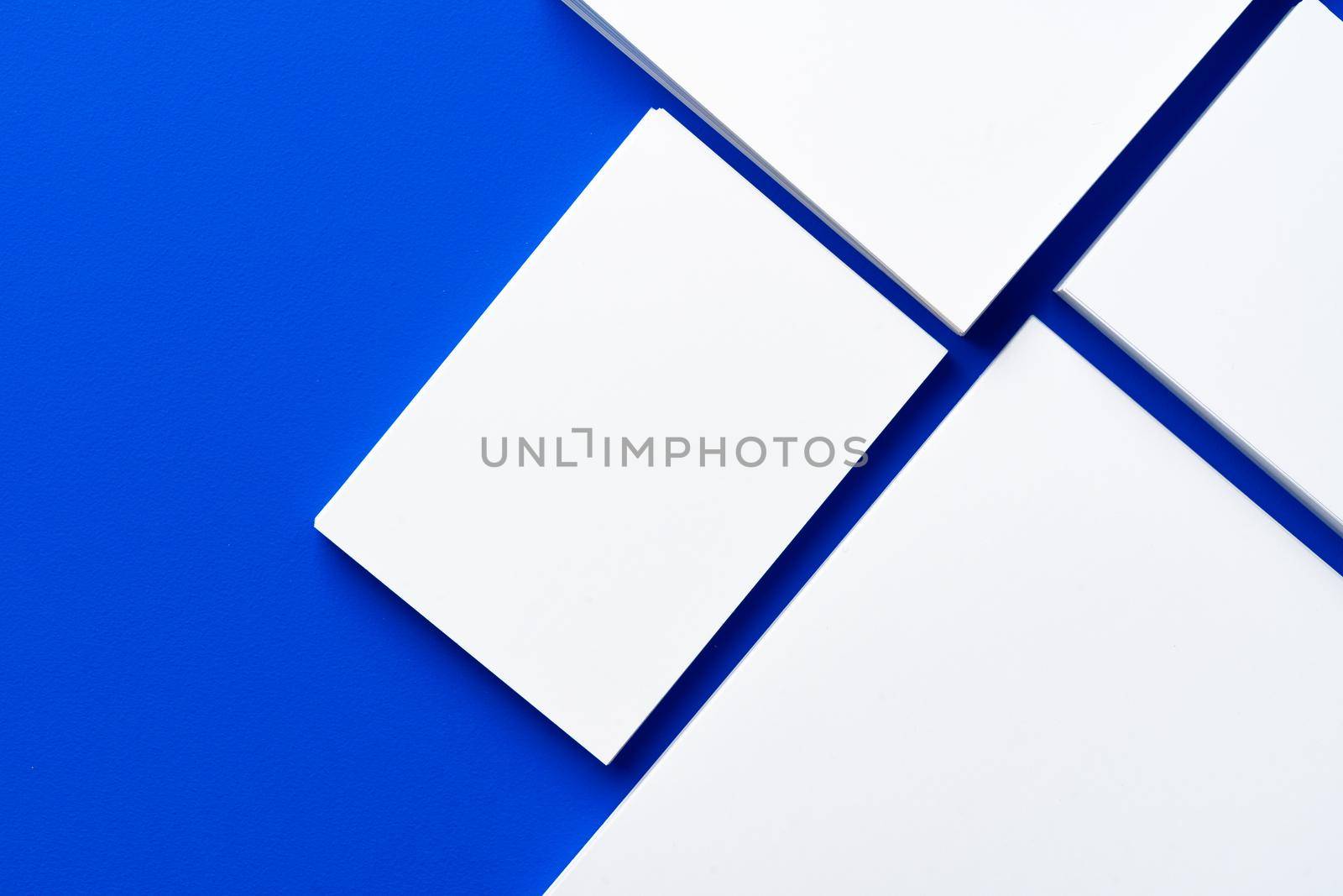 Blank white businesscards on classic blue background, copy space