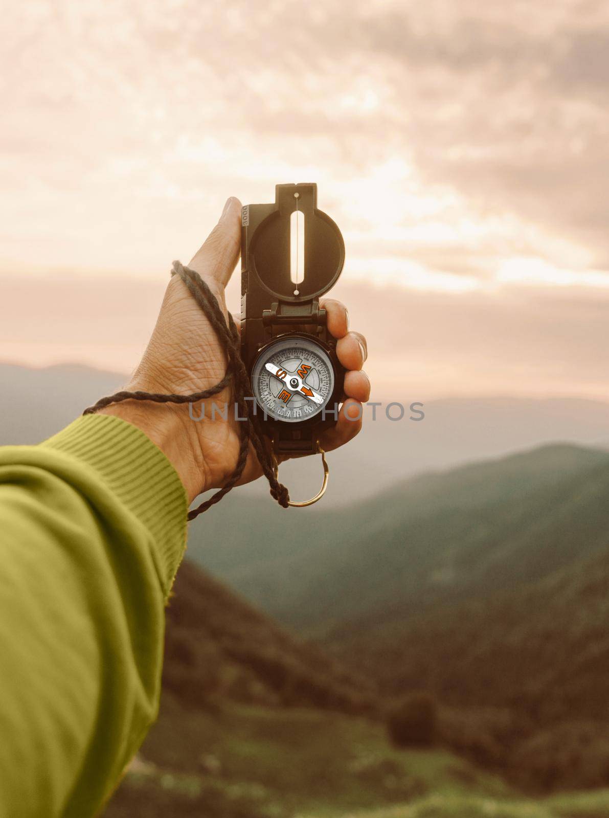 Male traveler explorer searching direction with compass in summer mountains, point of view.
