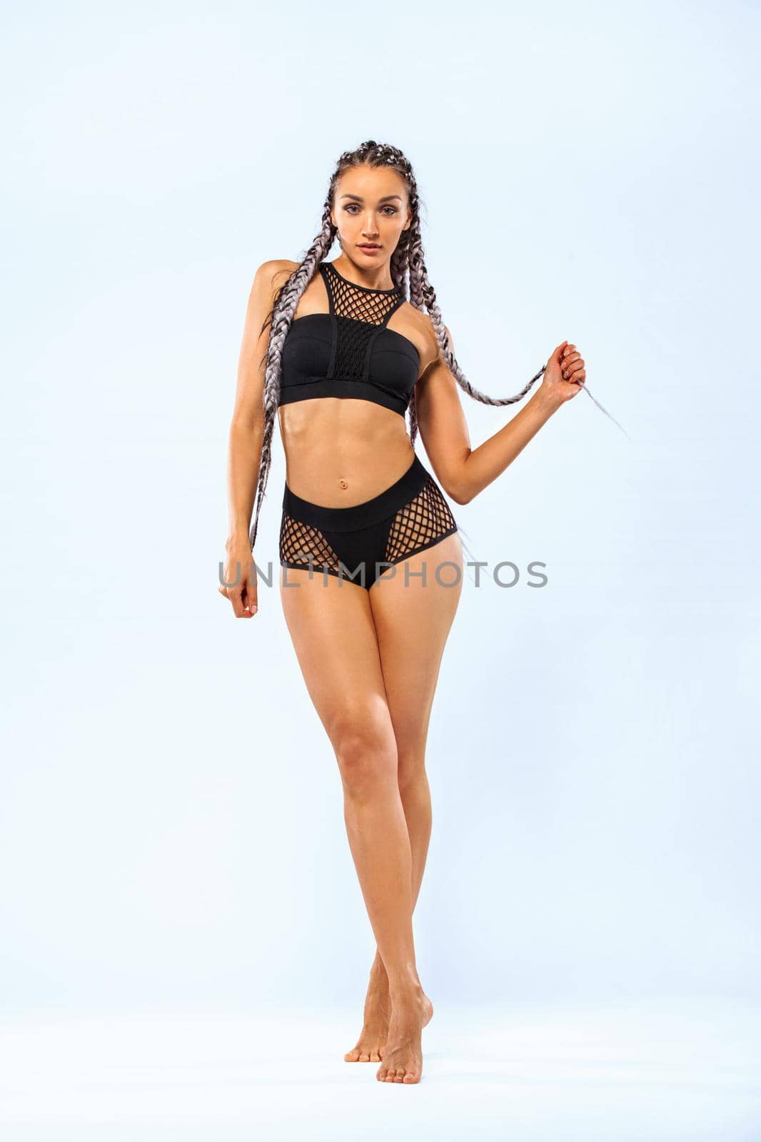 Fitness girl dancer in sportwear bikini with african pigtails isolated over white background by MikeOrlov