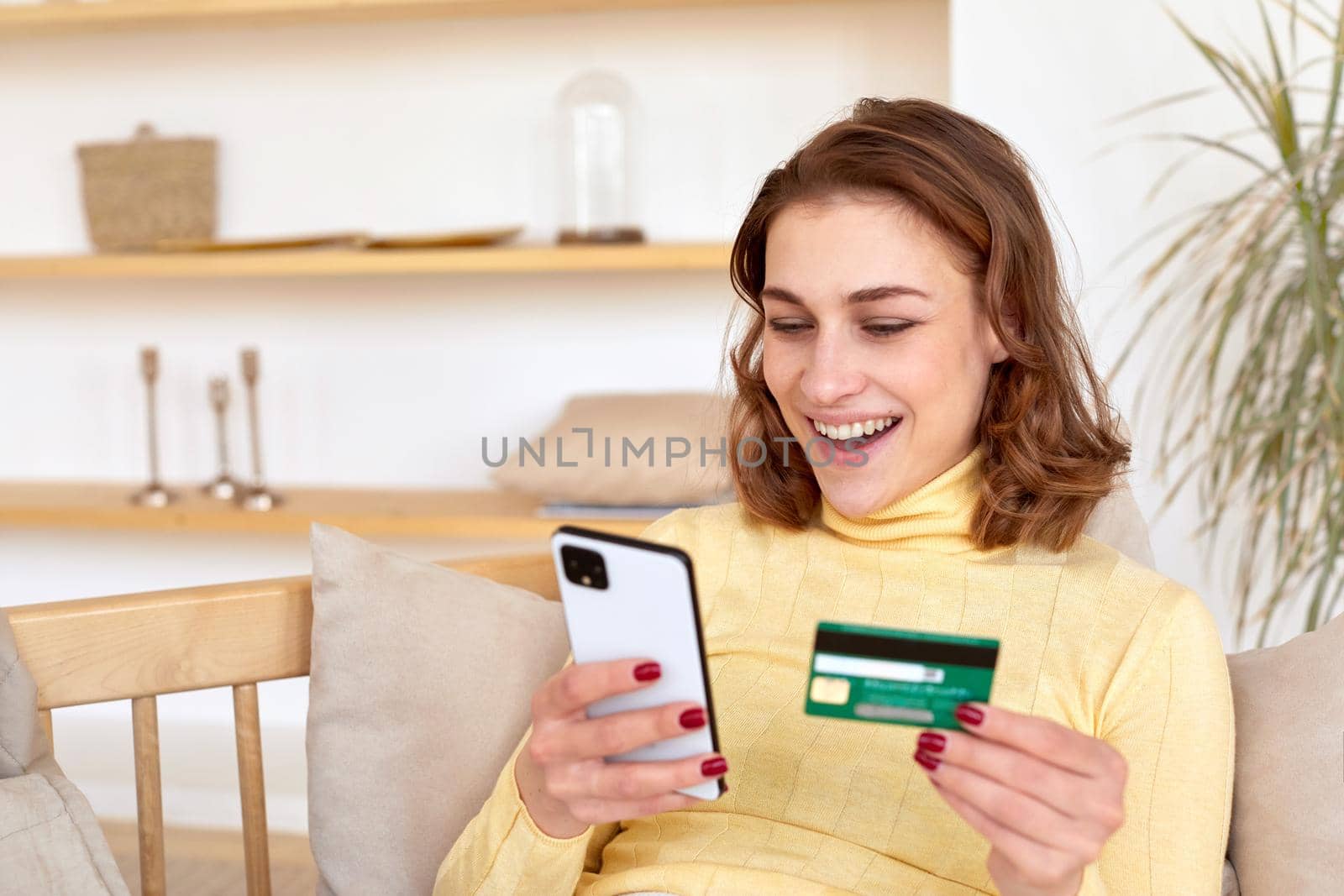 Smiling woman paying by card for online purchase by phone by Demkat