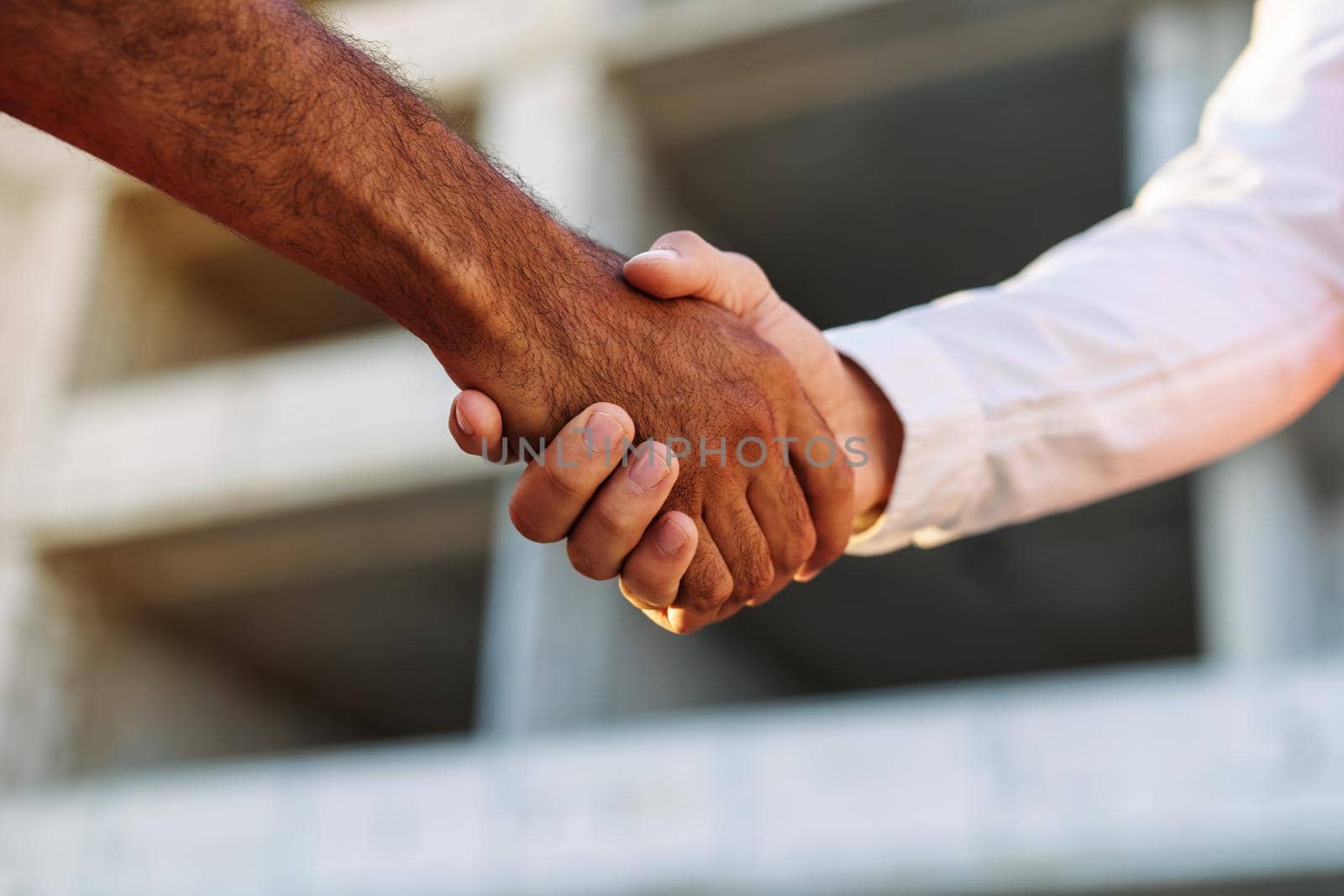 Close up photo of two men shaking hands against construction site