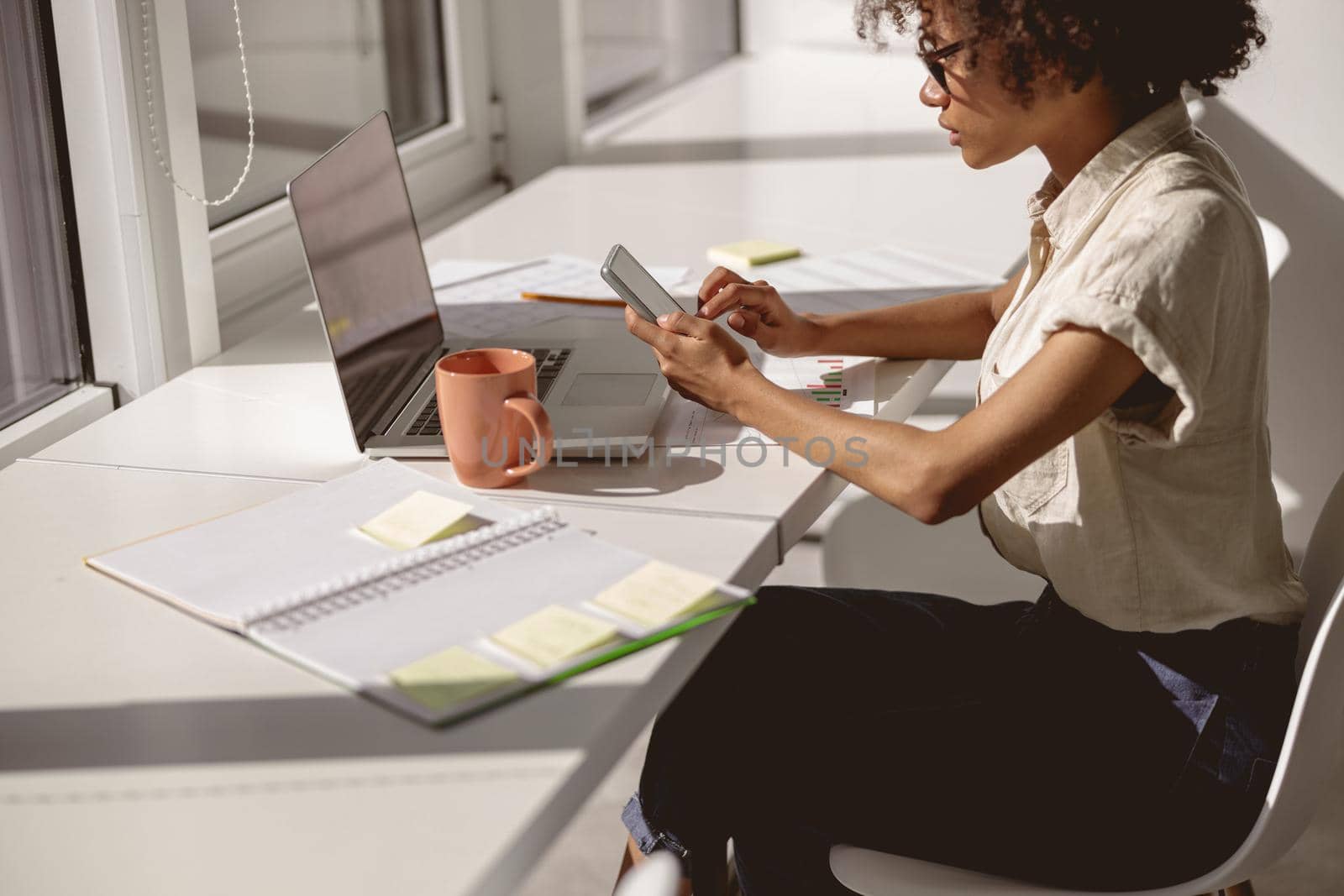 Cropped photo of young lady sitting at workplace and typing message on smartphone