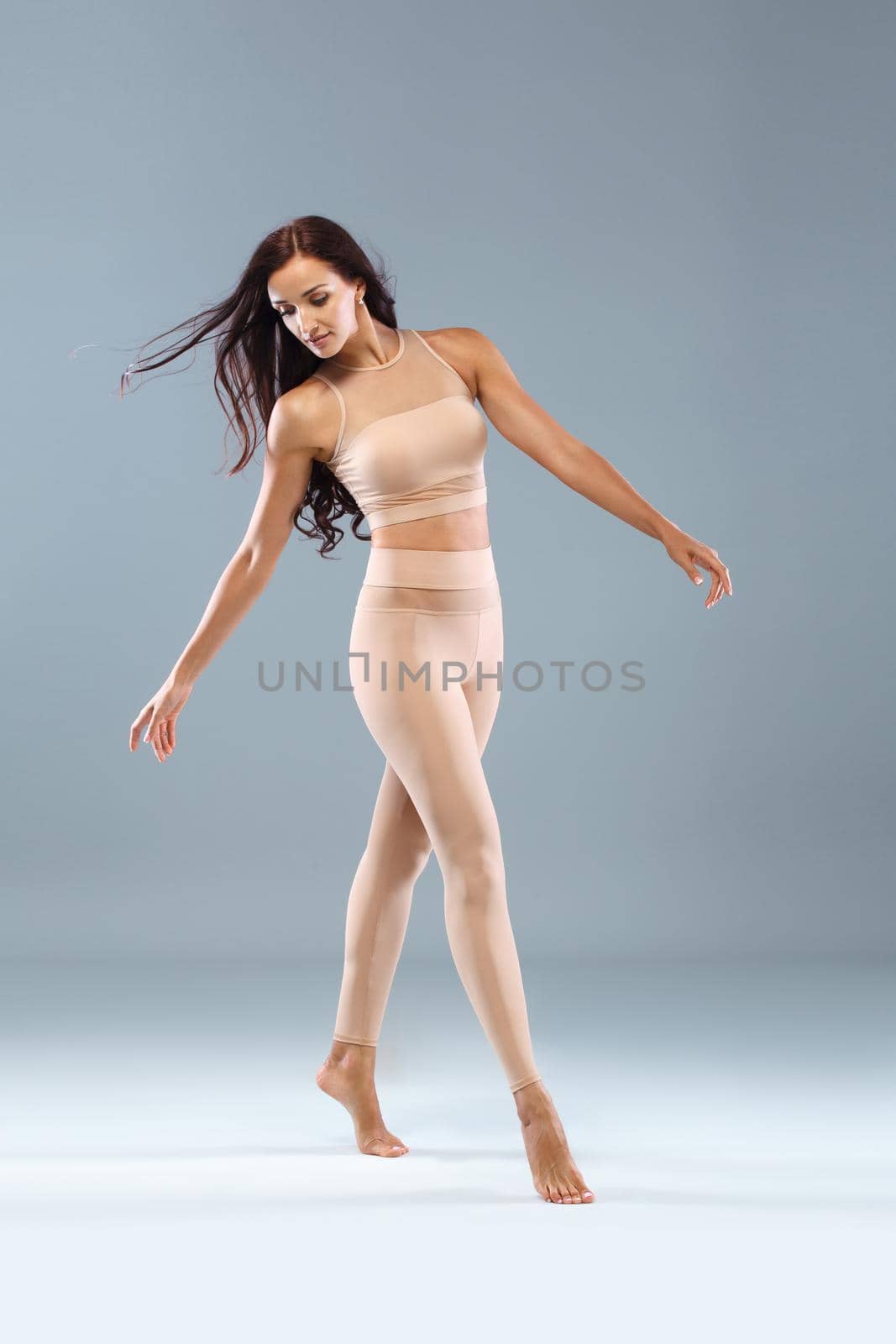 Attractive excited fitness girl in sportwear jumping of joy isolated over light background