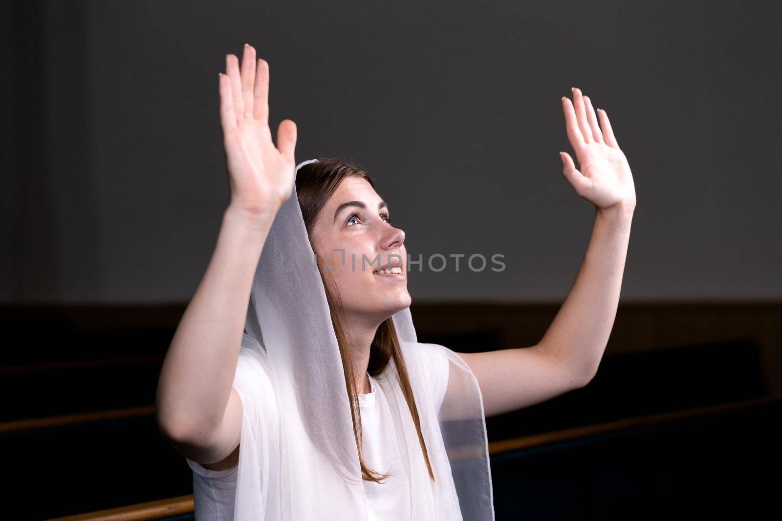 A young modest girl with a handkerchief on her head is sitting in church and praying. The concept of religion, prayer, worship.