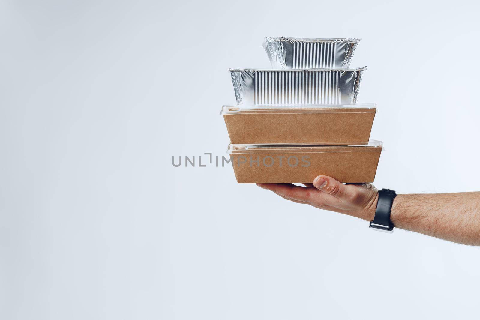 Courier hands giving packed food delivery close up against grey background