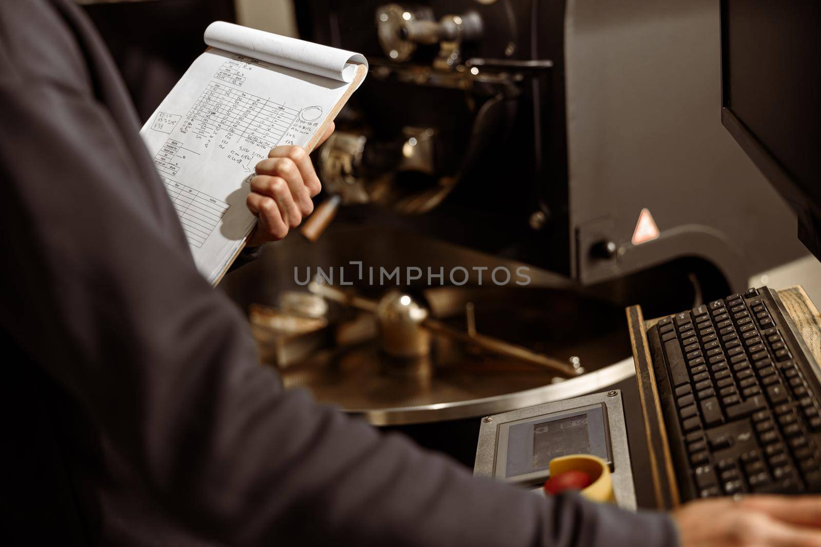 Young specialist worker is roasting coffee in hangar