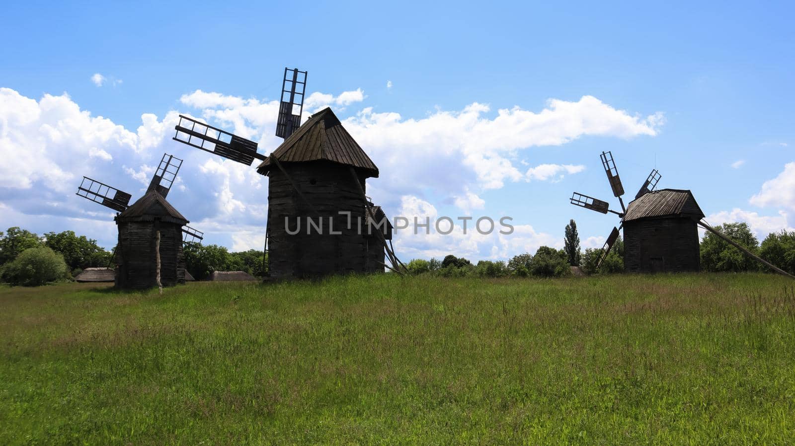 Ukraine, Kiev - June 11, 2020. Old Ukrainian wooden windmills of the XIX century. Summer outdoor landscape. Open-air museum of folk architecture and life, Pirogovo, Ukraine. Tourism and travel