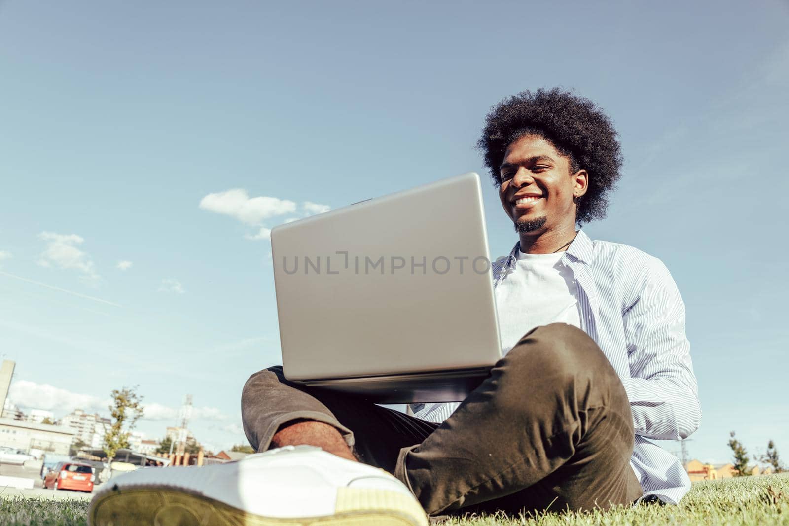 African american young man using laptop in park joyfully by ALVANPH