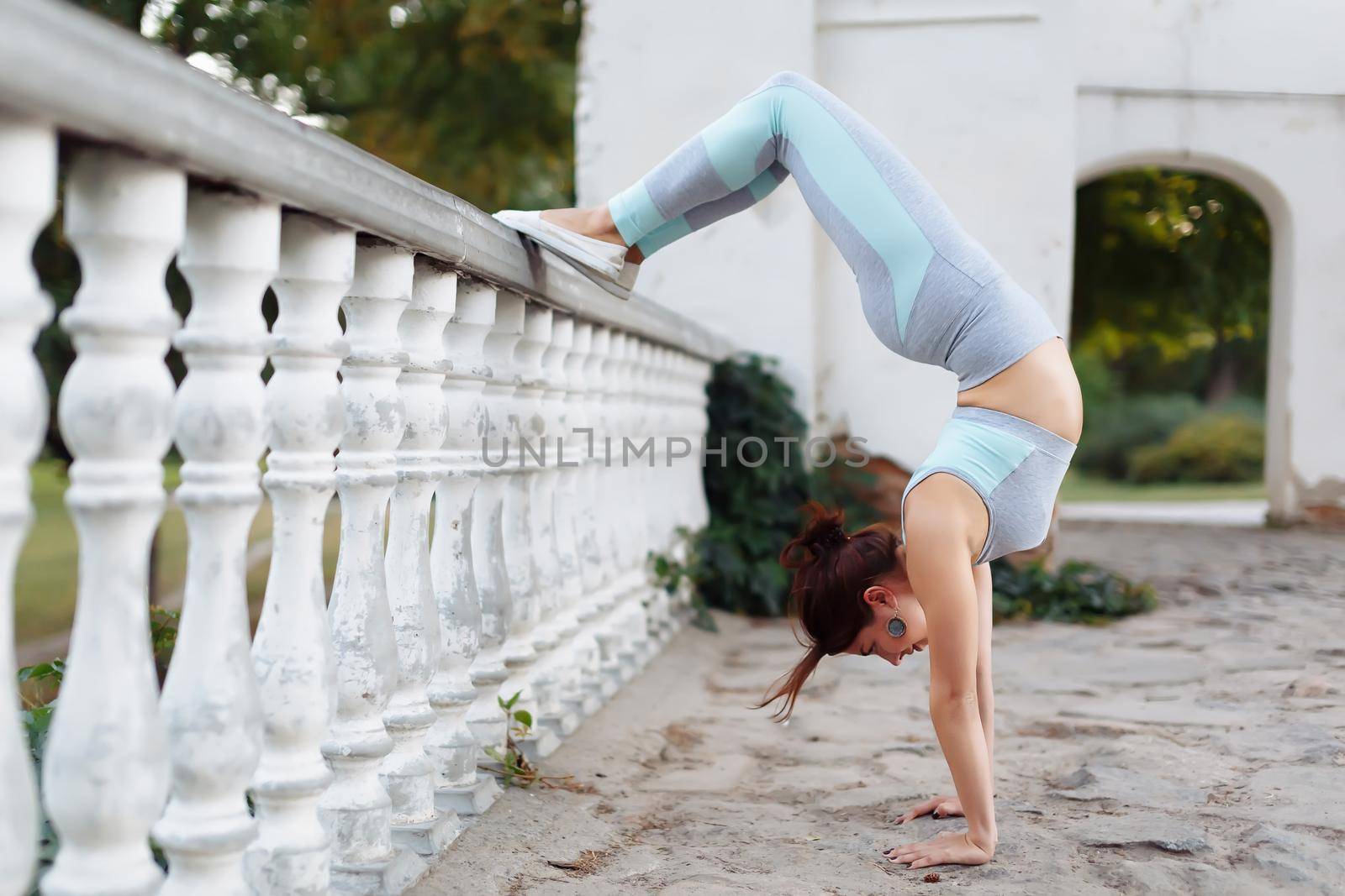 Pretty young woman doing yoga exercises in the park on the ruins