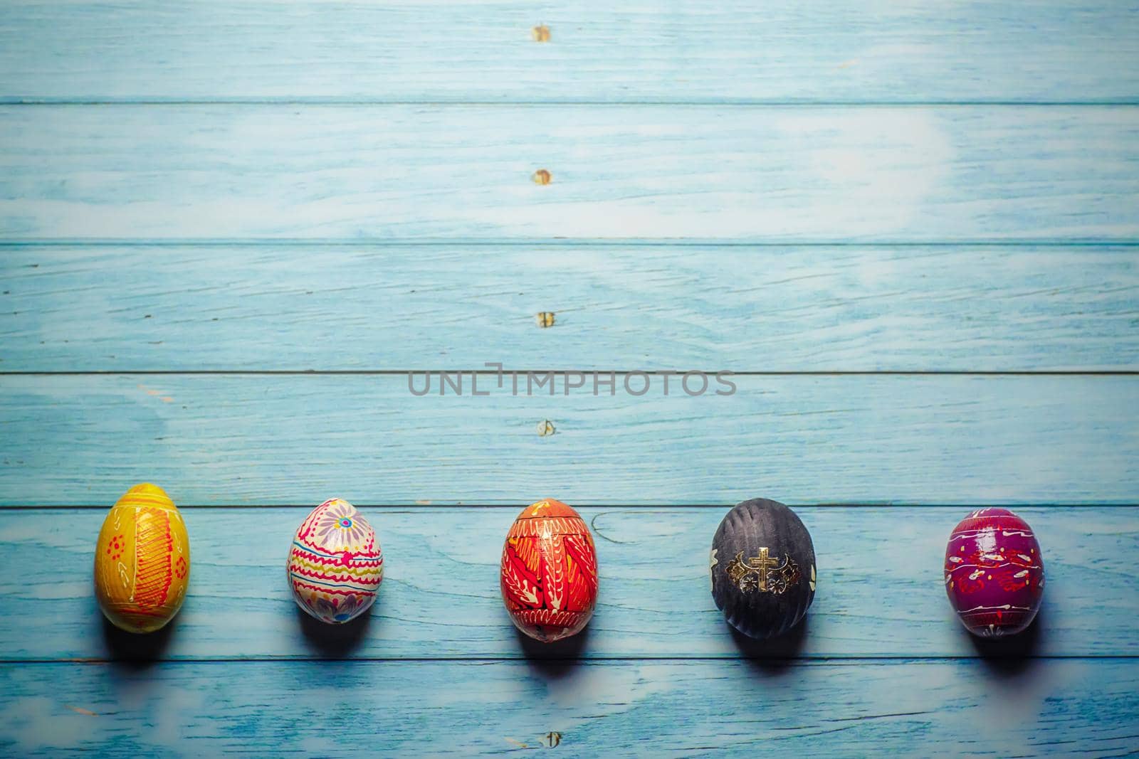 Easter colored painted eggs on blue wooden background flat lay with copy space