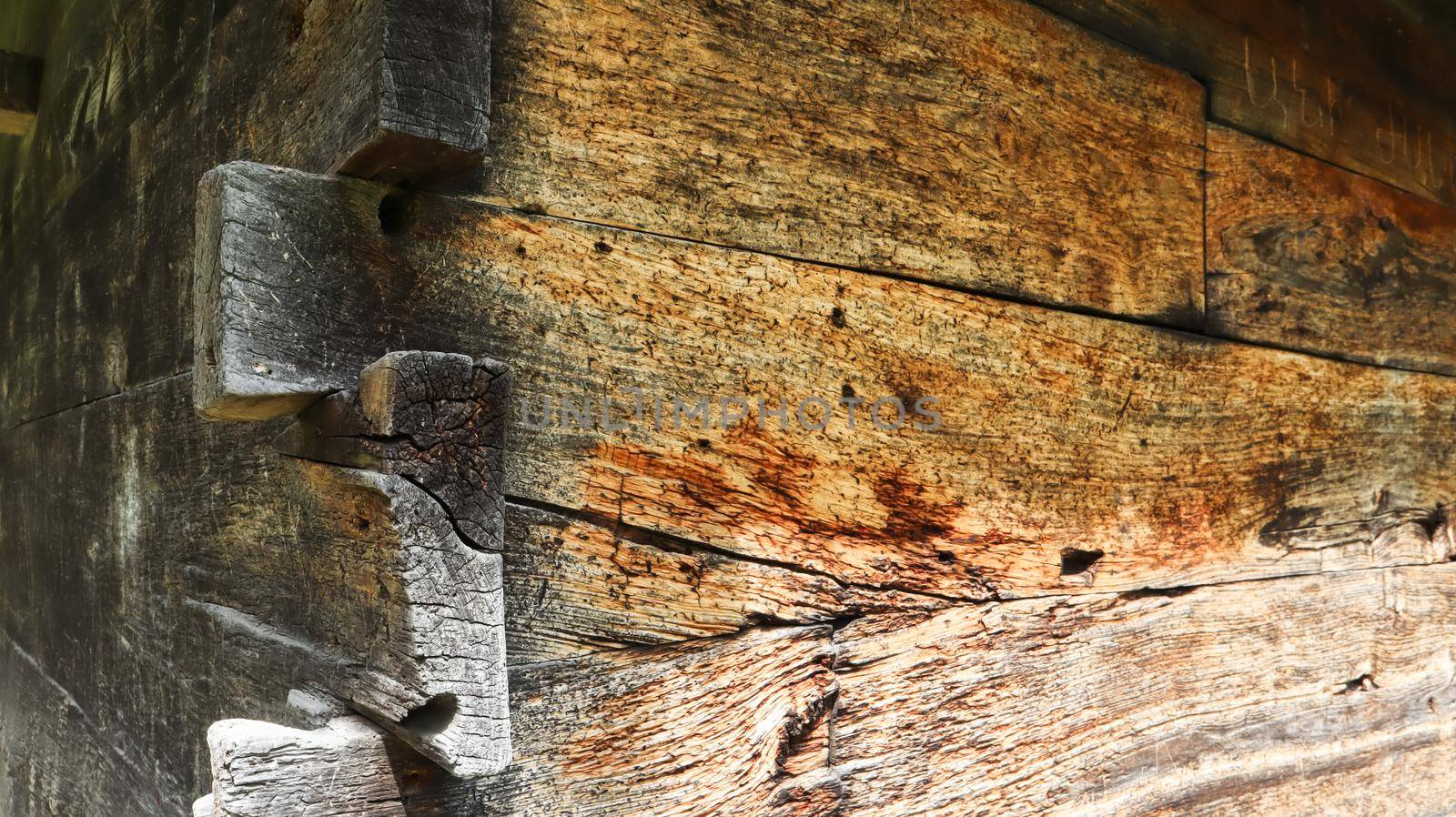 Wall, facade, corner of a wooden planed pine log house in the village. A brown rustic wood texture background. Architecture. Green building.