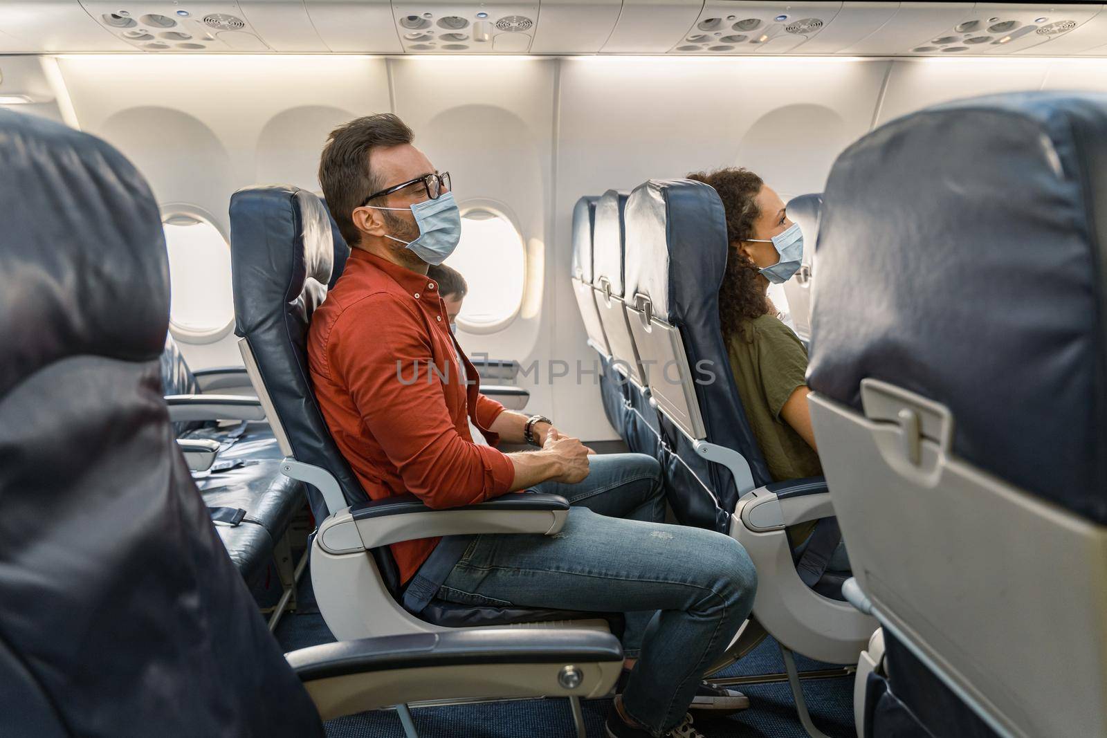 Male passenger with glasses resting in a chair during a flight in an airplane by Yaroslav_astakhov