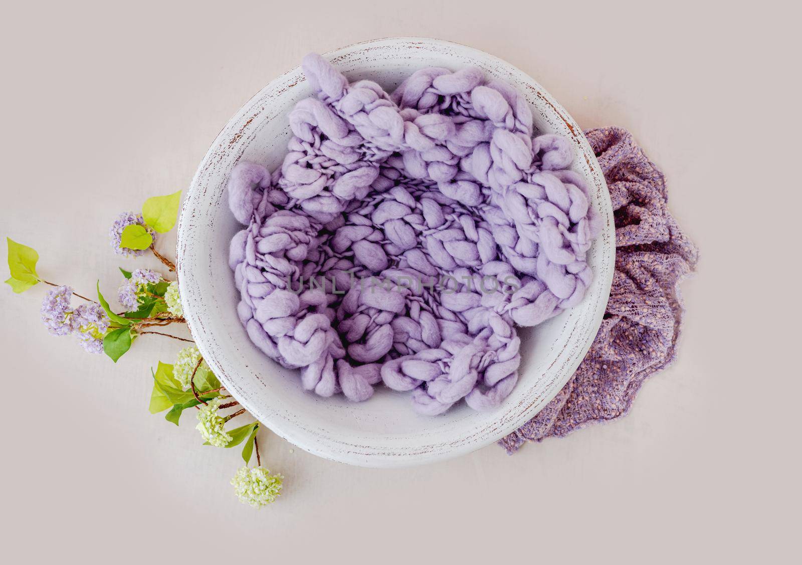 Beautiful backdrop for newborn photosession with flowers hydrangea. Digital composite with basin filled with knitted blanket isolated on light pink background