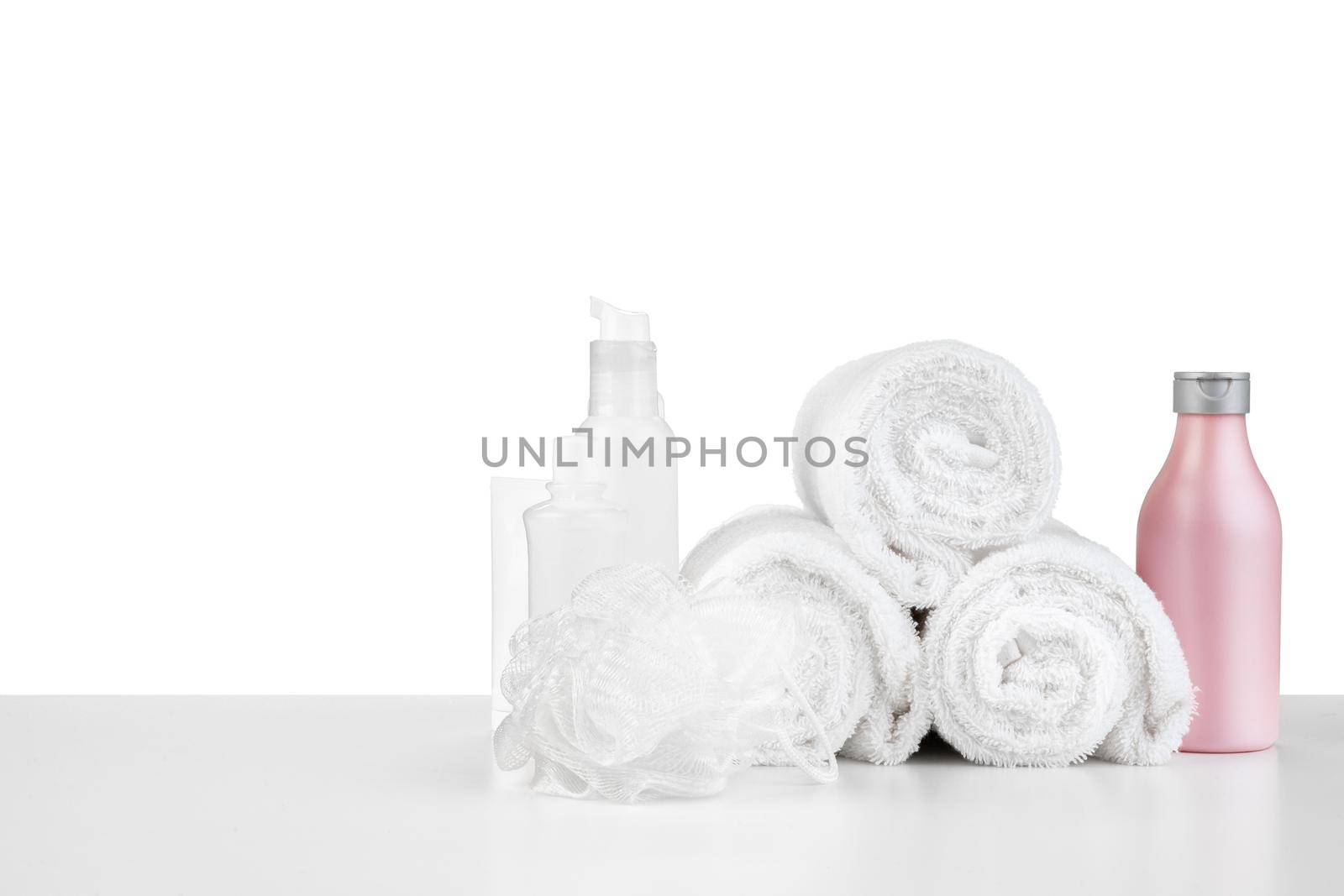 Composition of cosmetic bottles and towels isolated on white background