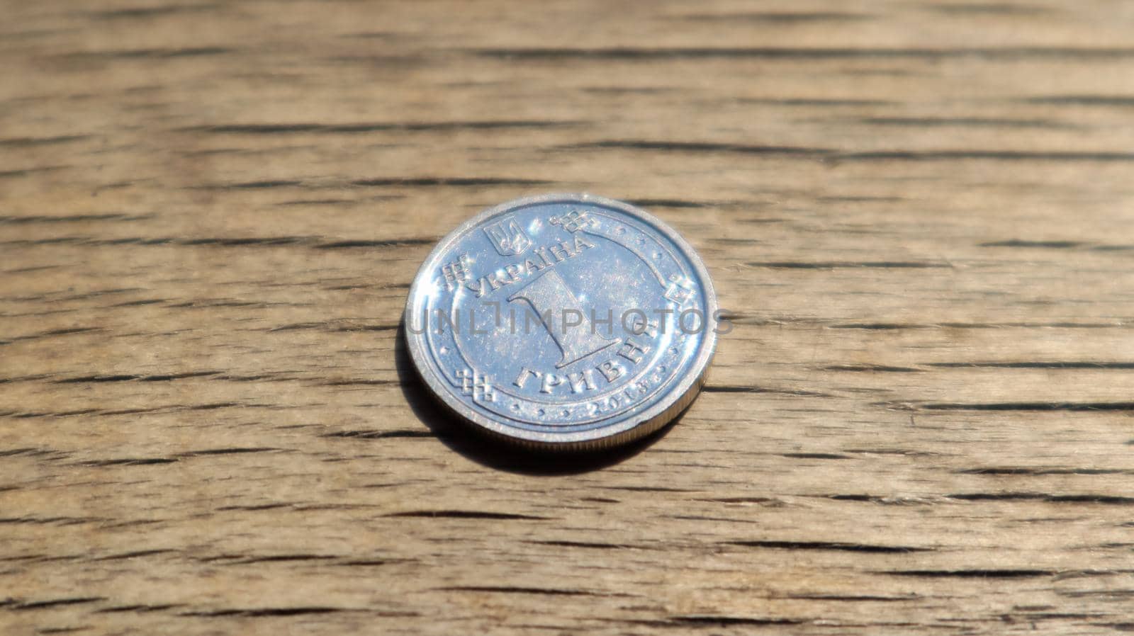 One new 2018 hryvnia coin on a wooden background. Ukrainian money.