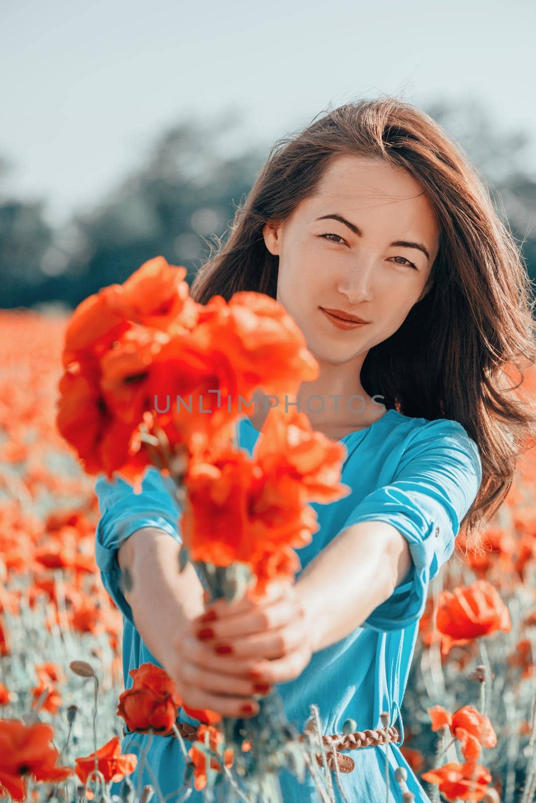 Smiling woman giving a bouquet of poppies. by alexAleksei
