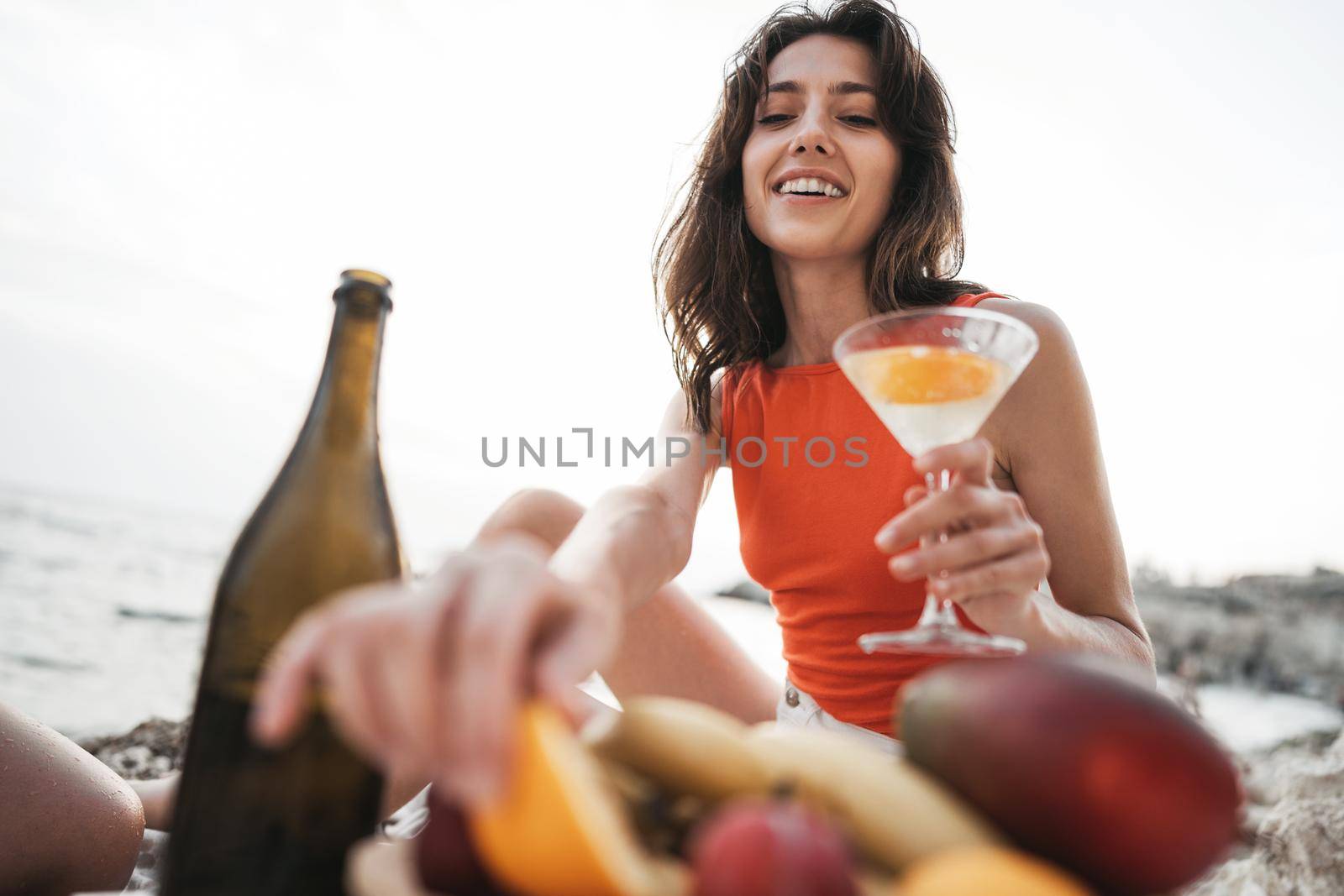 Portrait of young woman with cocktail glass chilling on a beach, close up