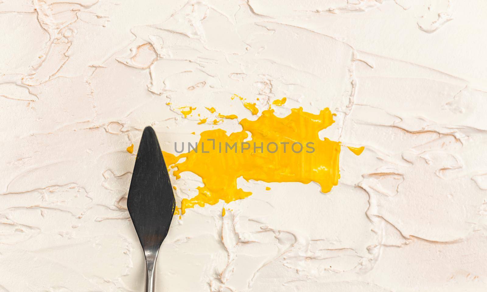 a painting palette knife isolated on a cream painted background painting yellow with copy space
