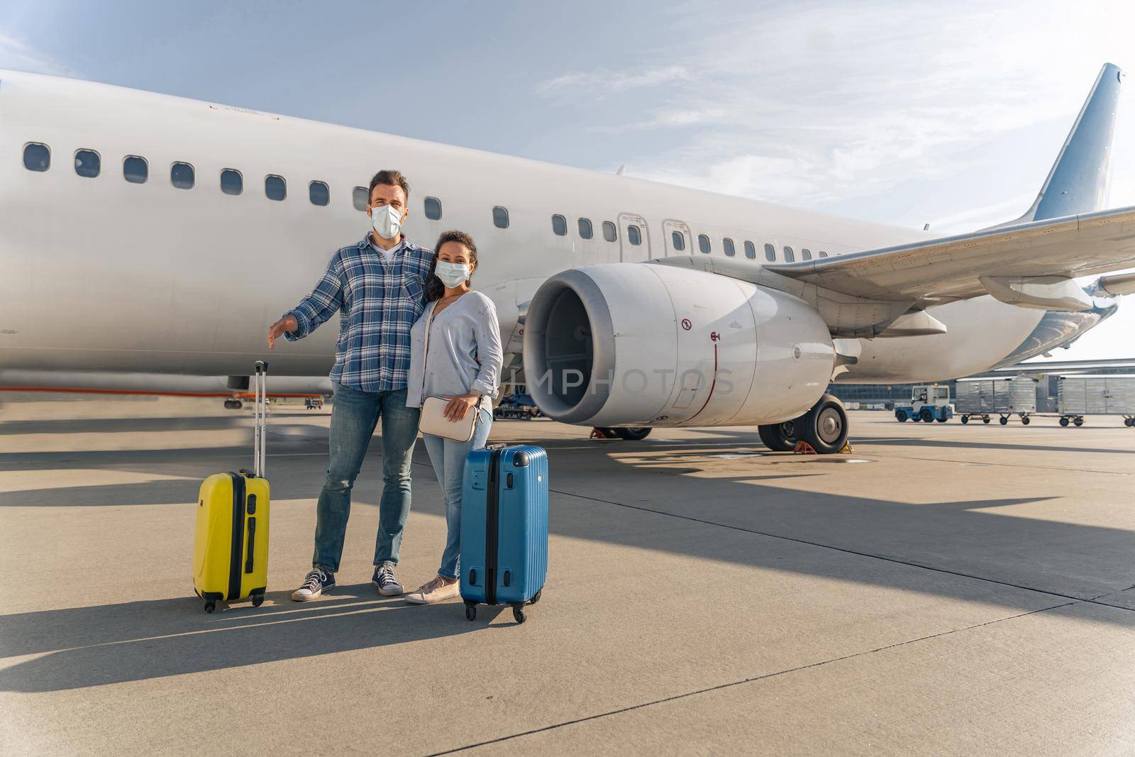 Man and woman with travel bags stansing near plane by Yaroslav_astakhov