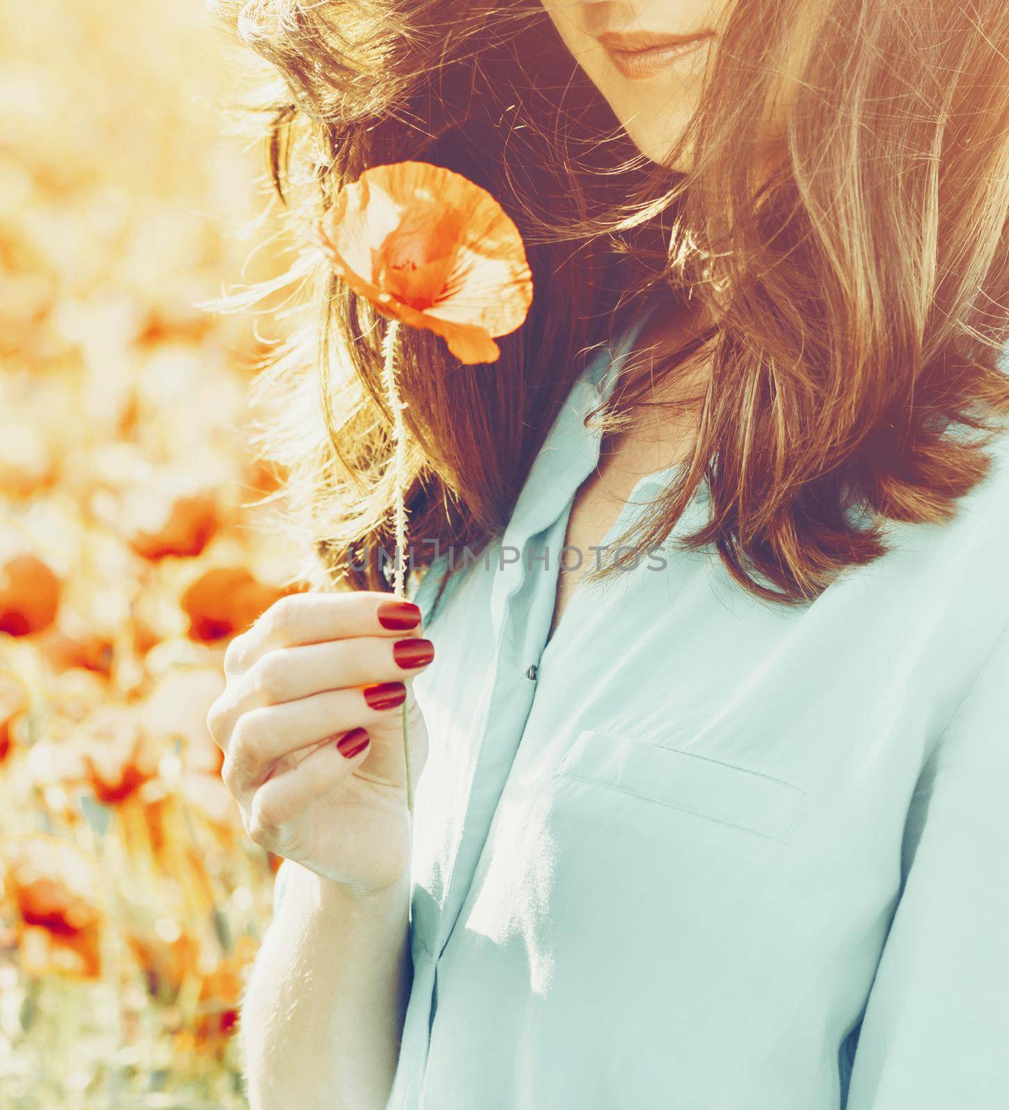 Smiling woman holding poppy flower in spring outdoor. by alexAleksei