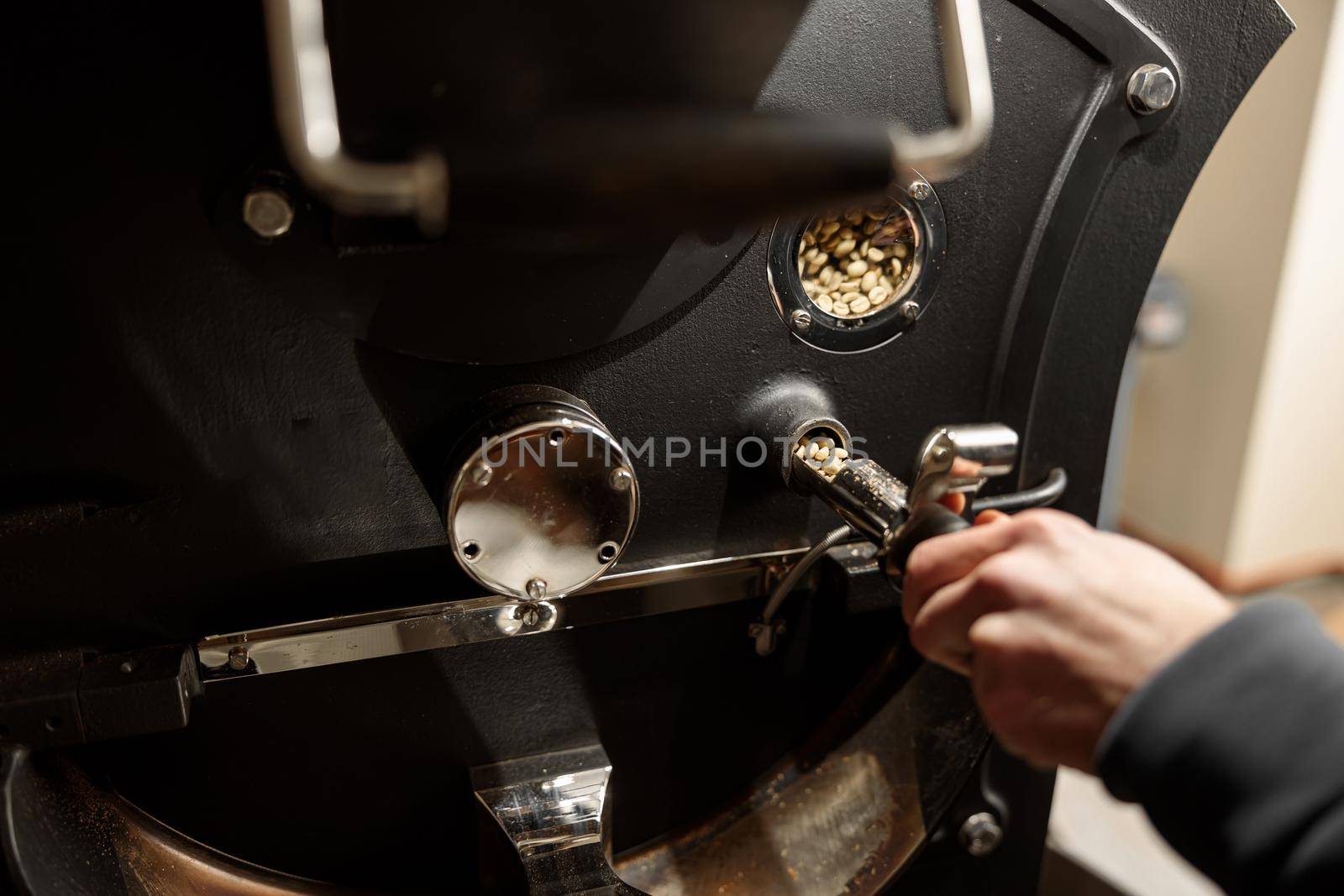 Young specialist worker is roasting coffee in hangar by Yaroslav_astakhov