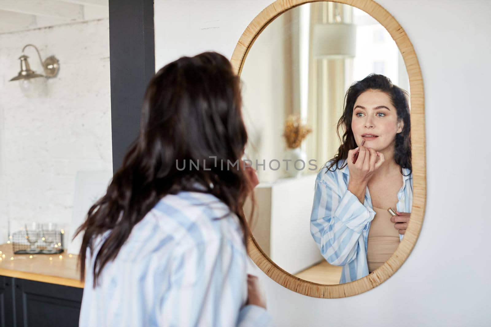 Woman applying makeup near mirror by Demkat