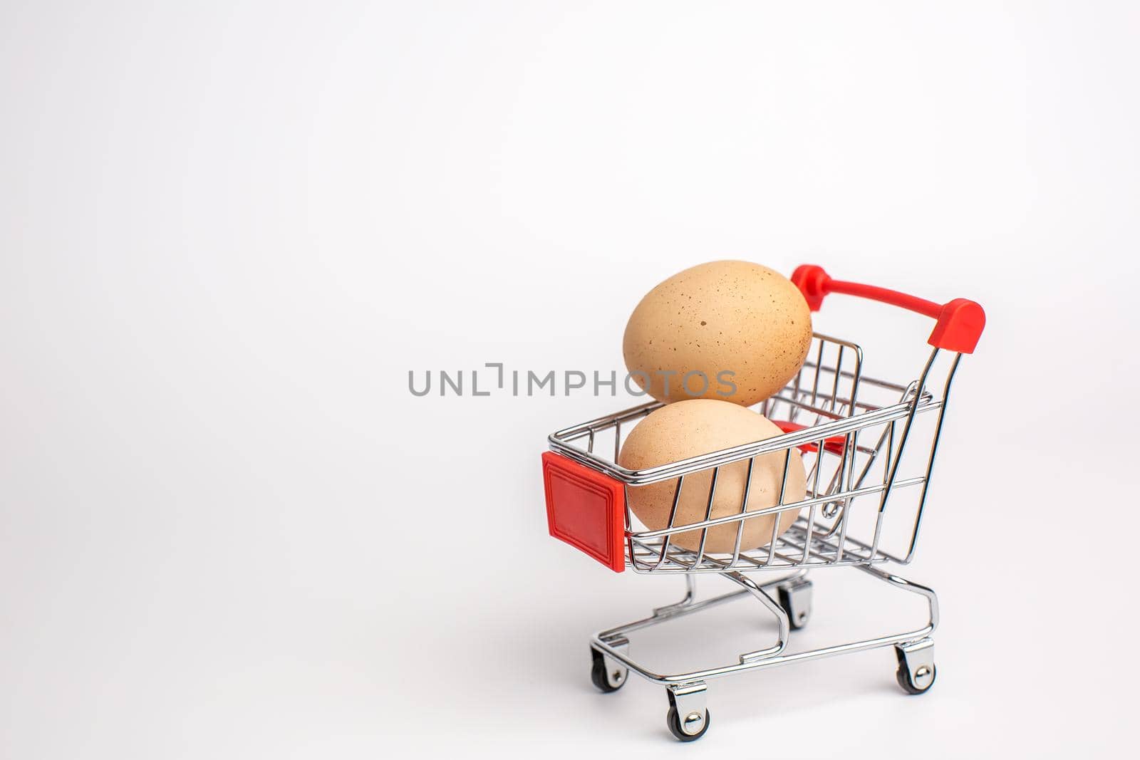 Beige chicken eggs in the shopping cart. White isolated background. Healthy food concept.