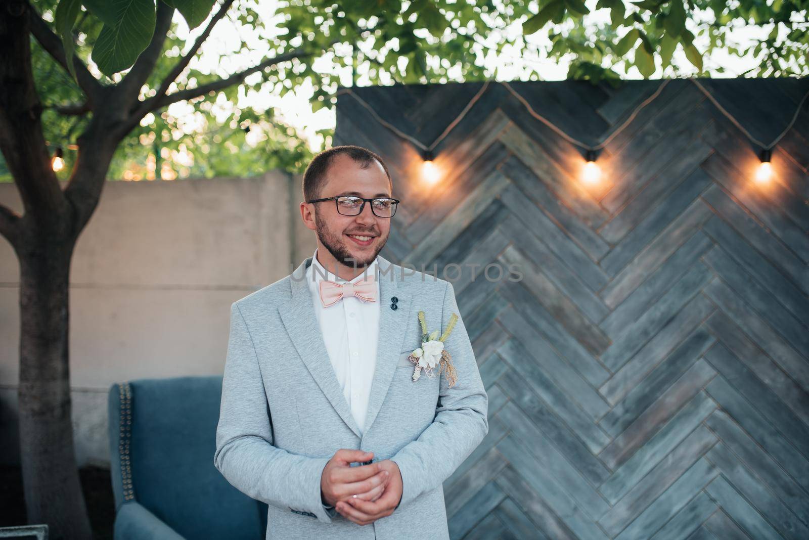 Wedding photo of emotions of a bearded groom with glasses in a gray jacket and rustic style by lunarts